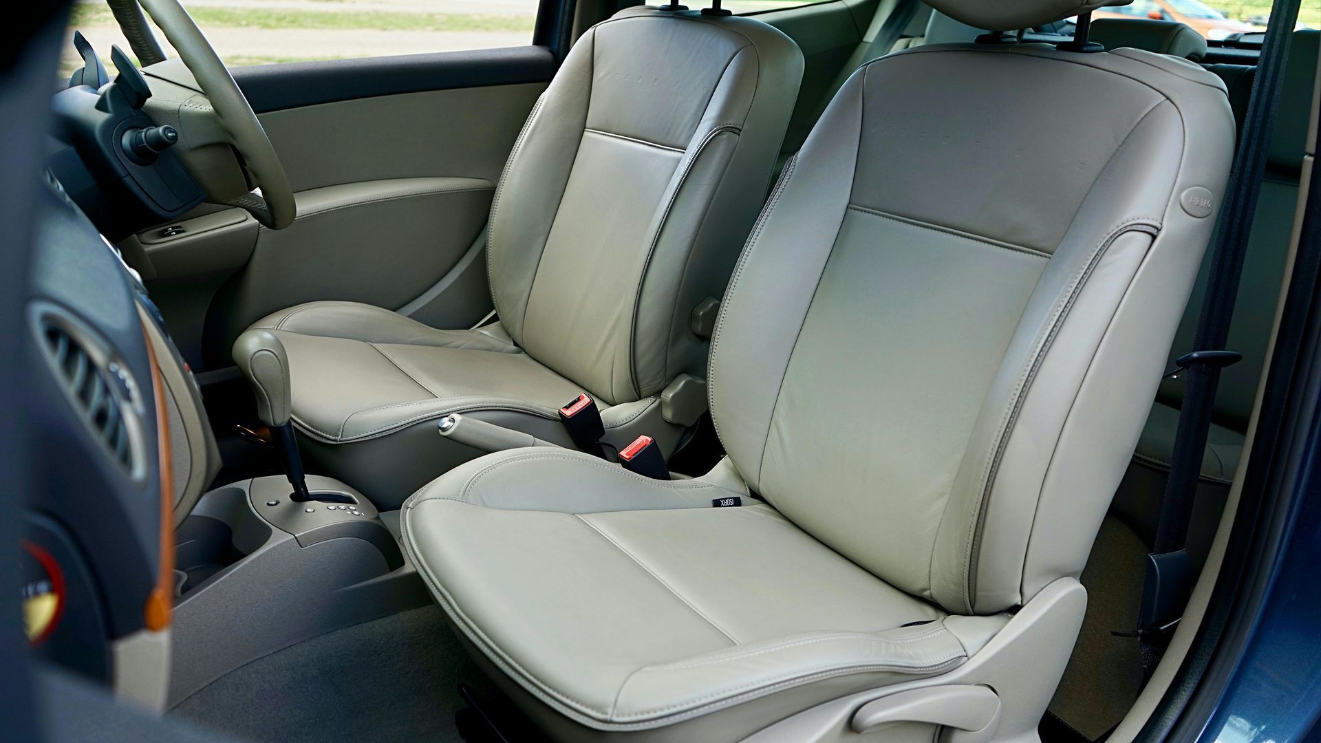 Front seats of a car with light gray leather upholstery and center console