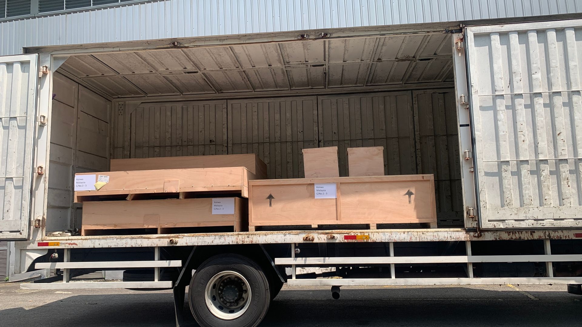 Truck cargo bed loaded with large cardboard boxes inside an open shipping container.