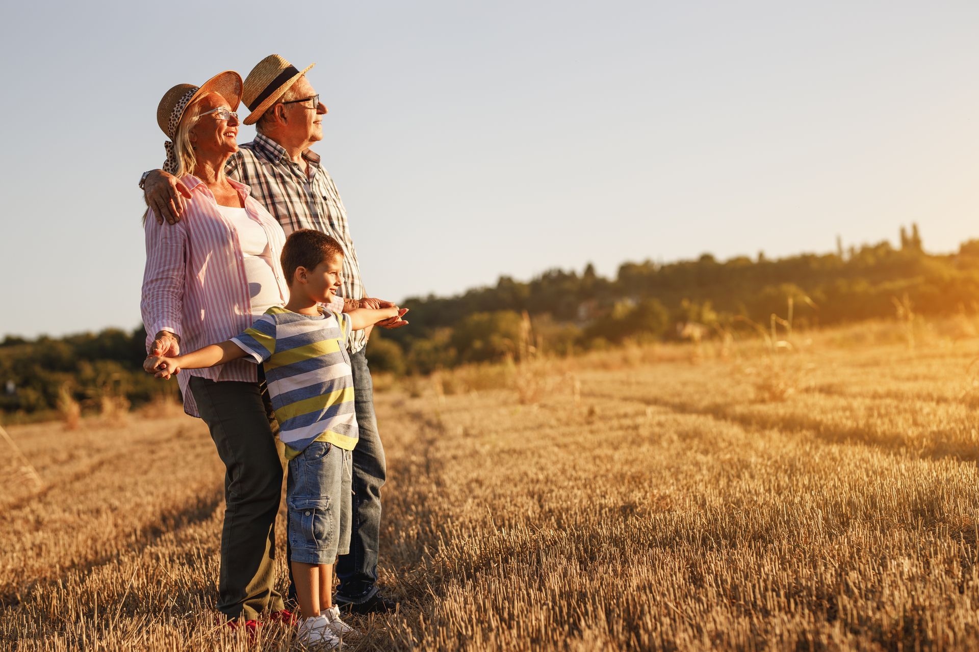 An elderly couple and a young boy are standing in a field.