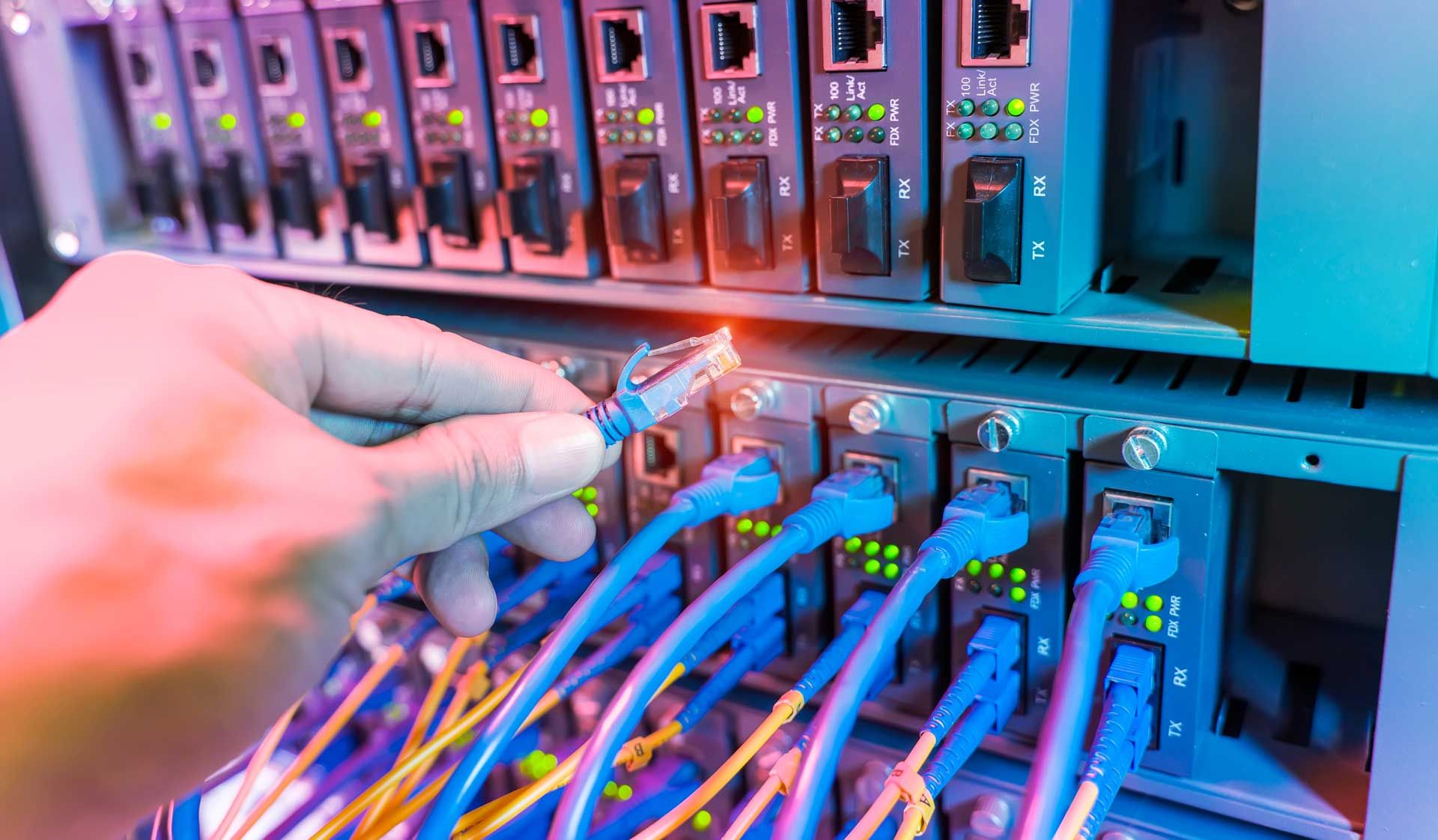A technician working in a network server room with fiber optic hub.