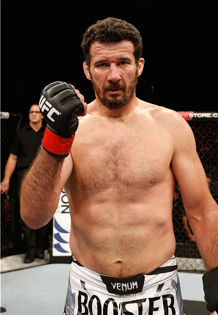 A shirtless fighter wearing a ufc glove and booster shorts