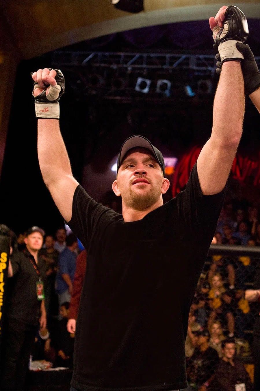 A man in a black shirt is raising his arms in the air