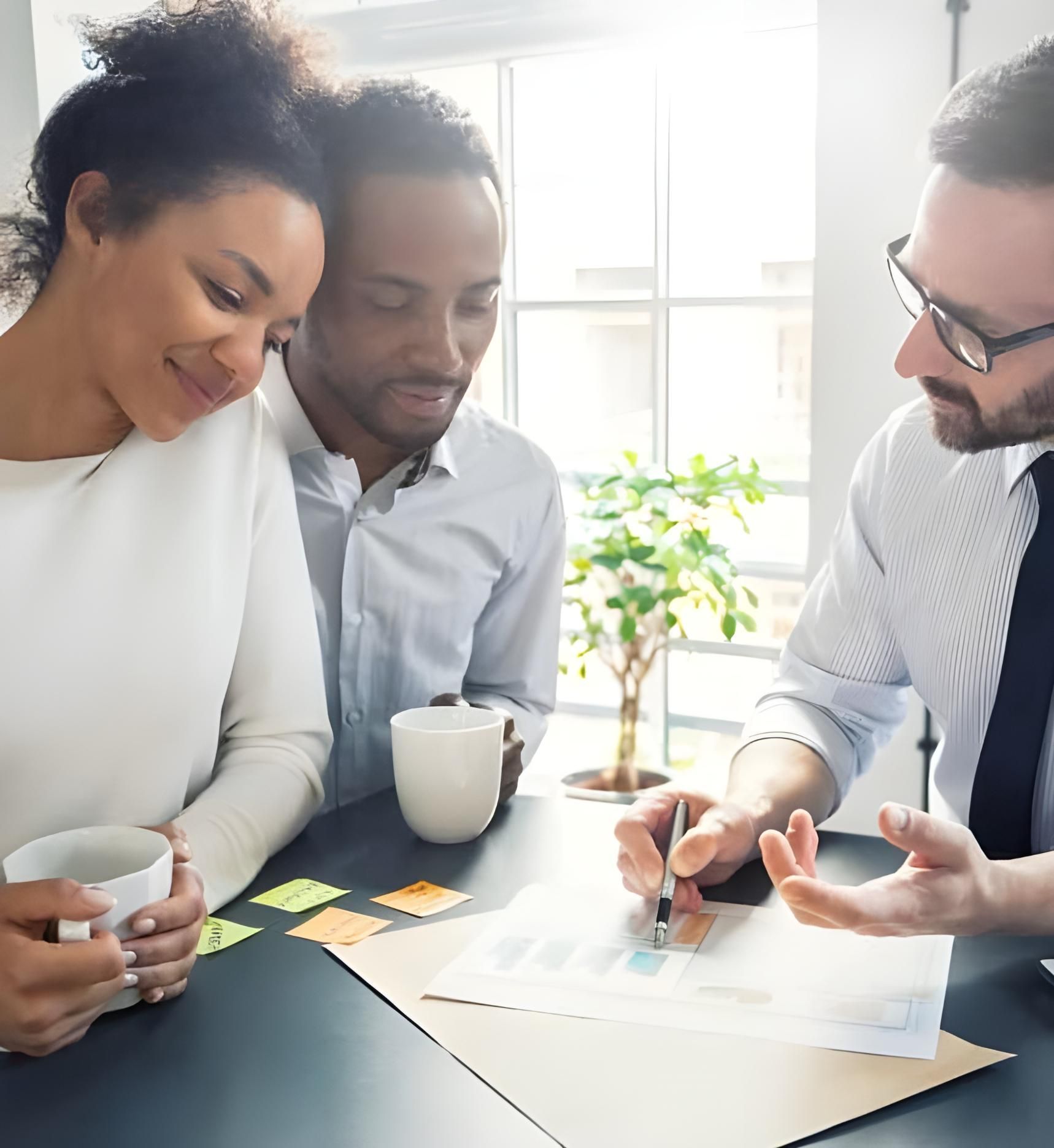 Two Men And A Woman Are Sitting On A Couch With A Man Writing On A Clipboard — Coast & Country Insurance Consultants Pty Ltd In Central Coast, NSW