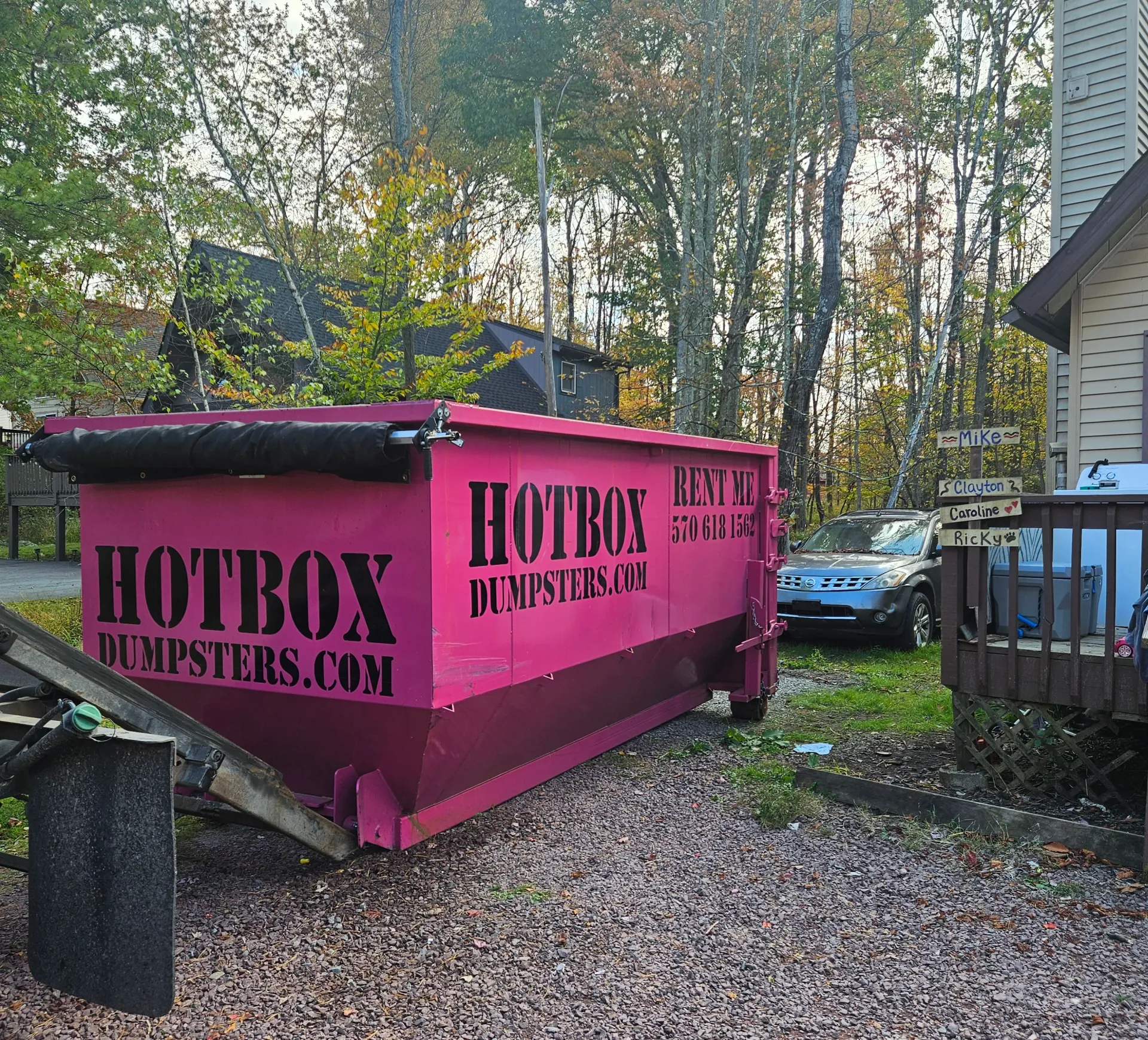 A green dumpster is parked in front of a house.