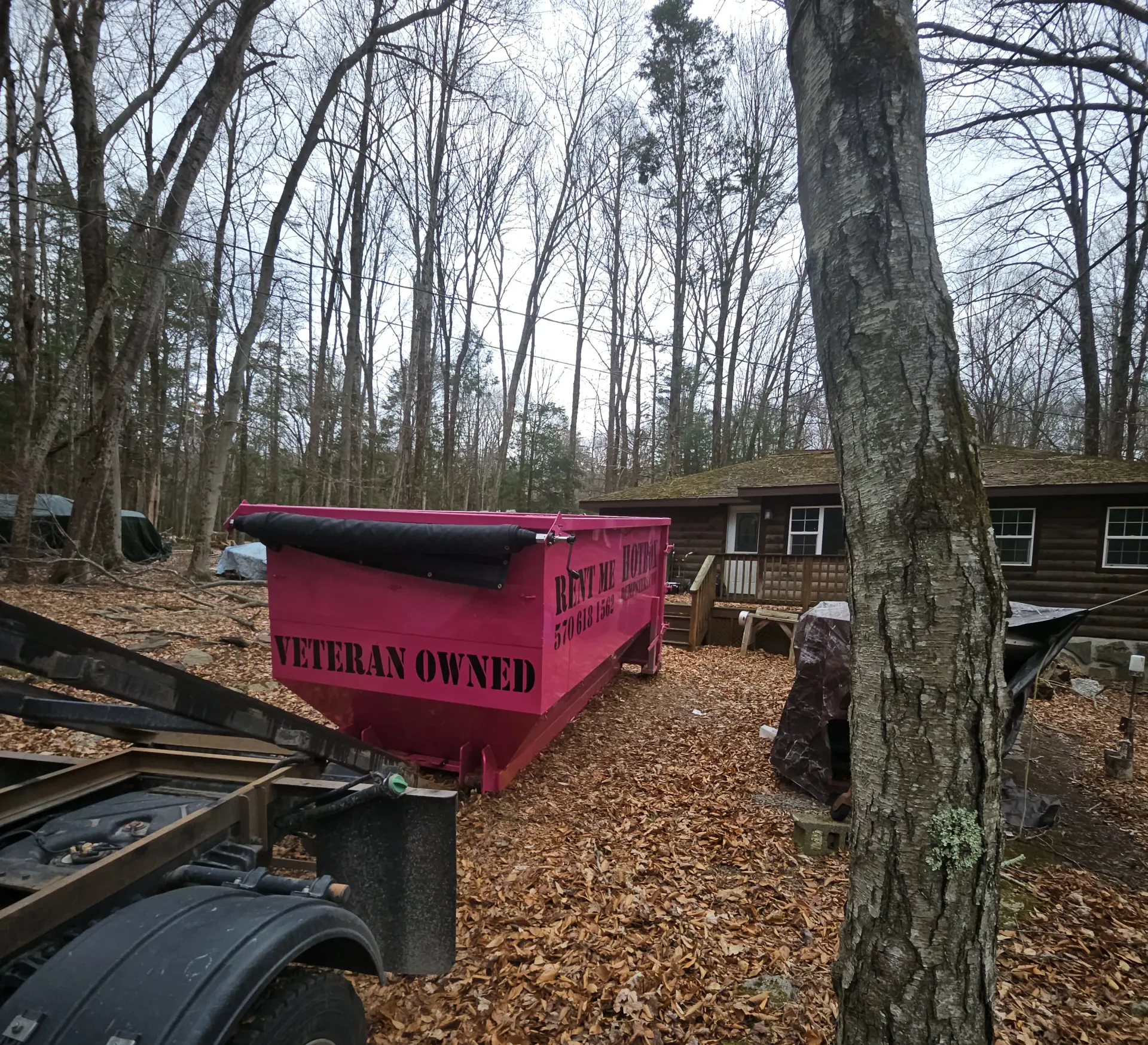A green dumpster is parked in front of a house.