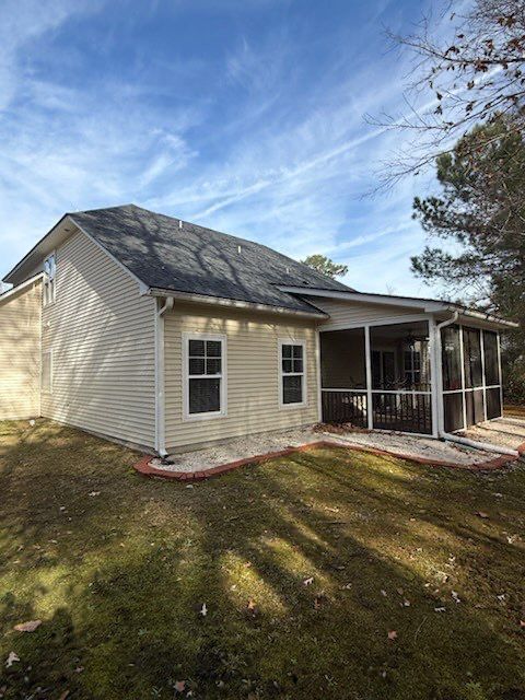 Tan house with screened porch, two windows, and dark roof under a blue sky.