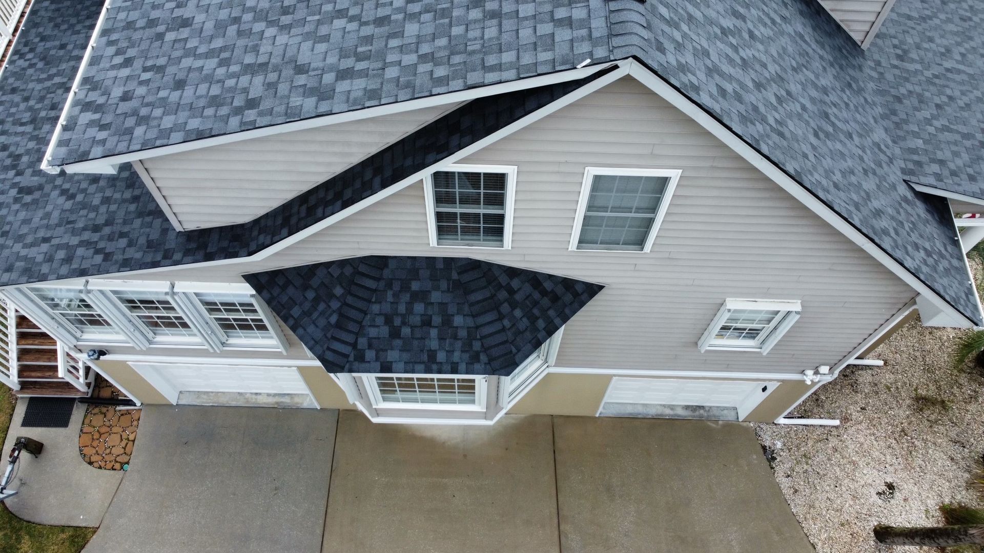 Overhead view of a two-story house with a gray roof and light gray siding, and a concrete driveway.
