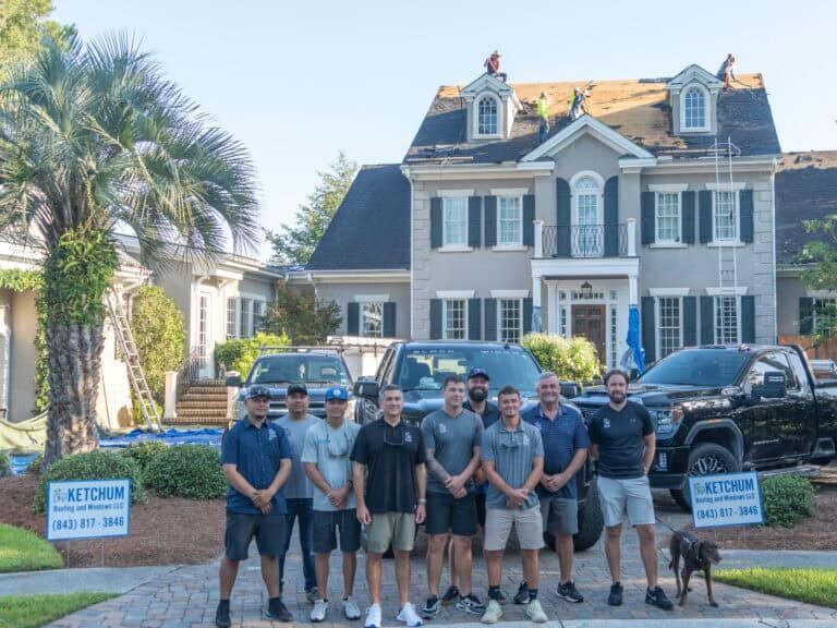 A group of men in front of a house with trucks; the men are likely a roofing crew.