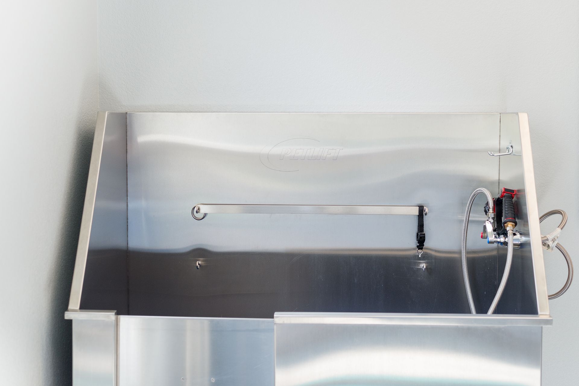 Stainless steel pet grooming tub in a room.