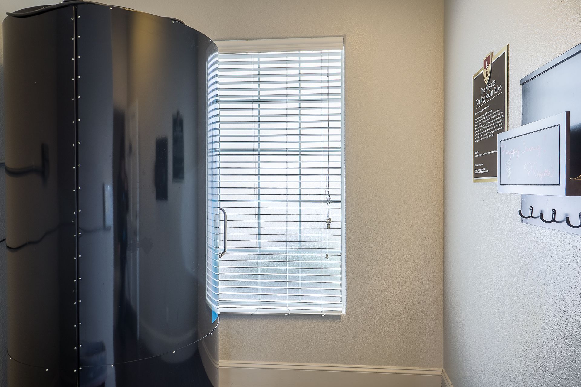 Black sauna, window with blinds, wall decor, and hooks.
