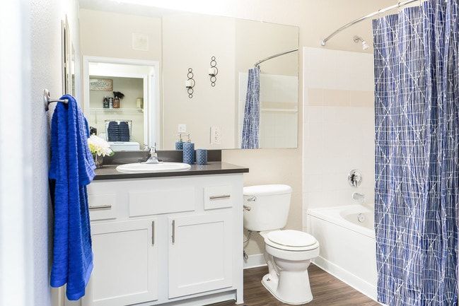 Bathroom with white vanity, blue towel, and shower curtain.
