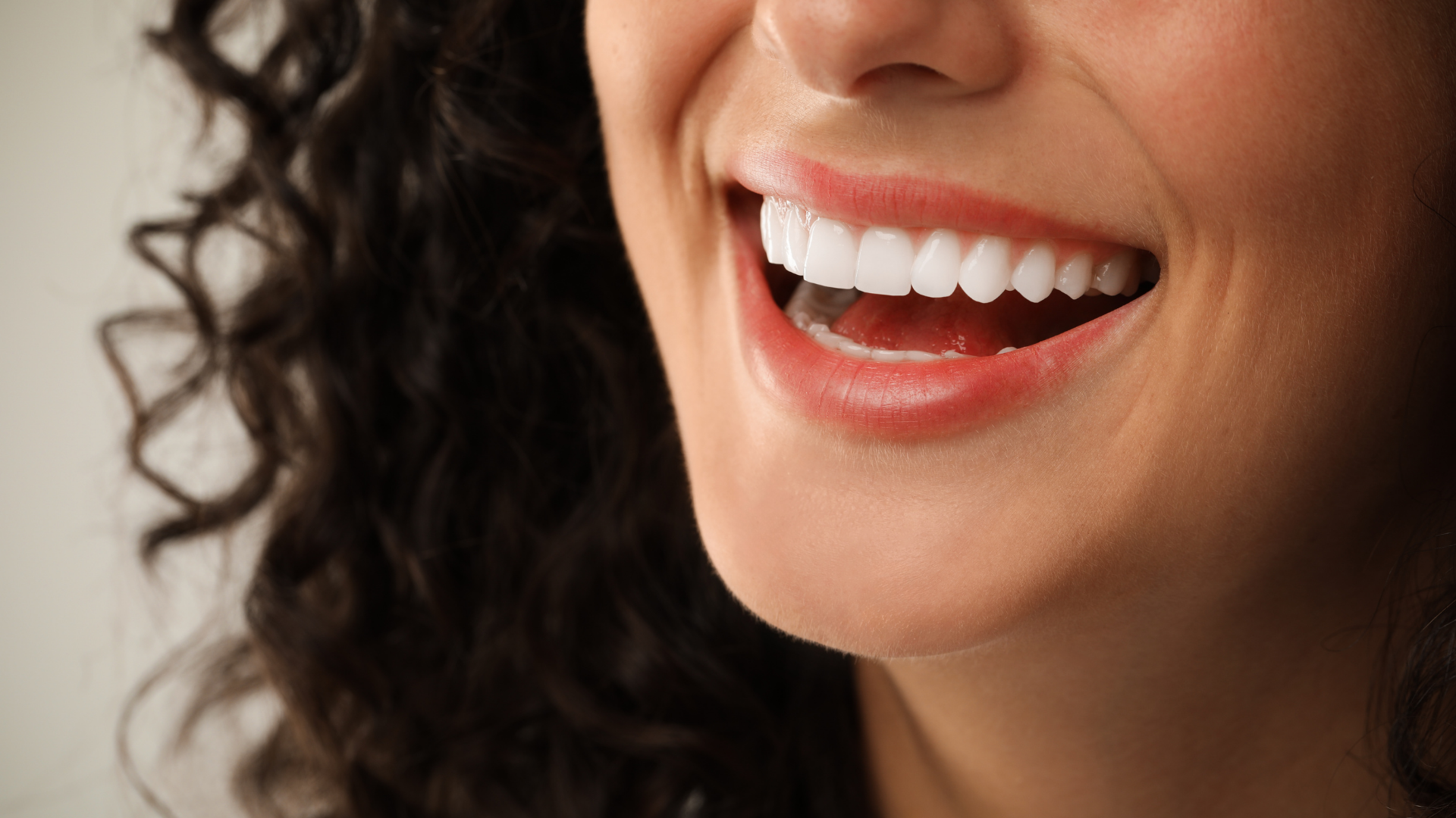 Smiling woman in a dentist’s office holding up a blue dental bib and giving thumbs up