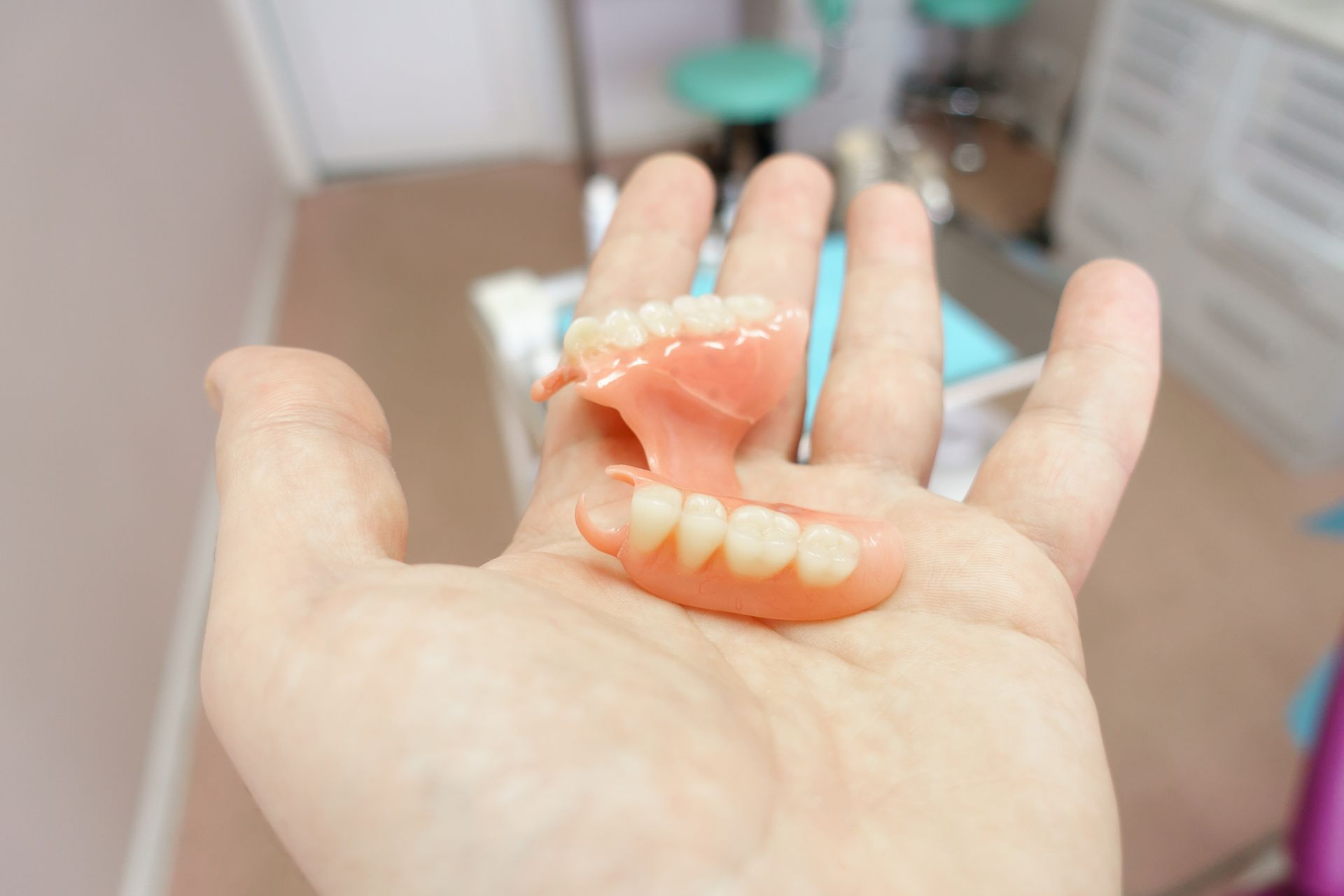 A dentist holding a denture, showcasing expert denture repair for a seamless, natural fit.