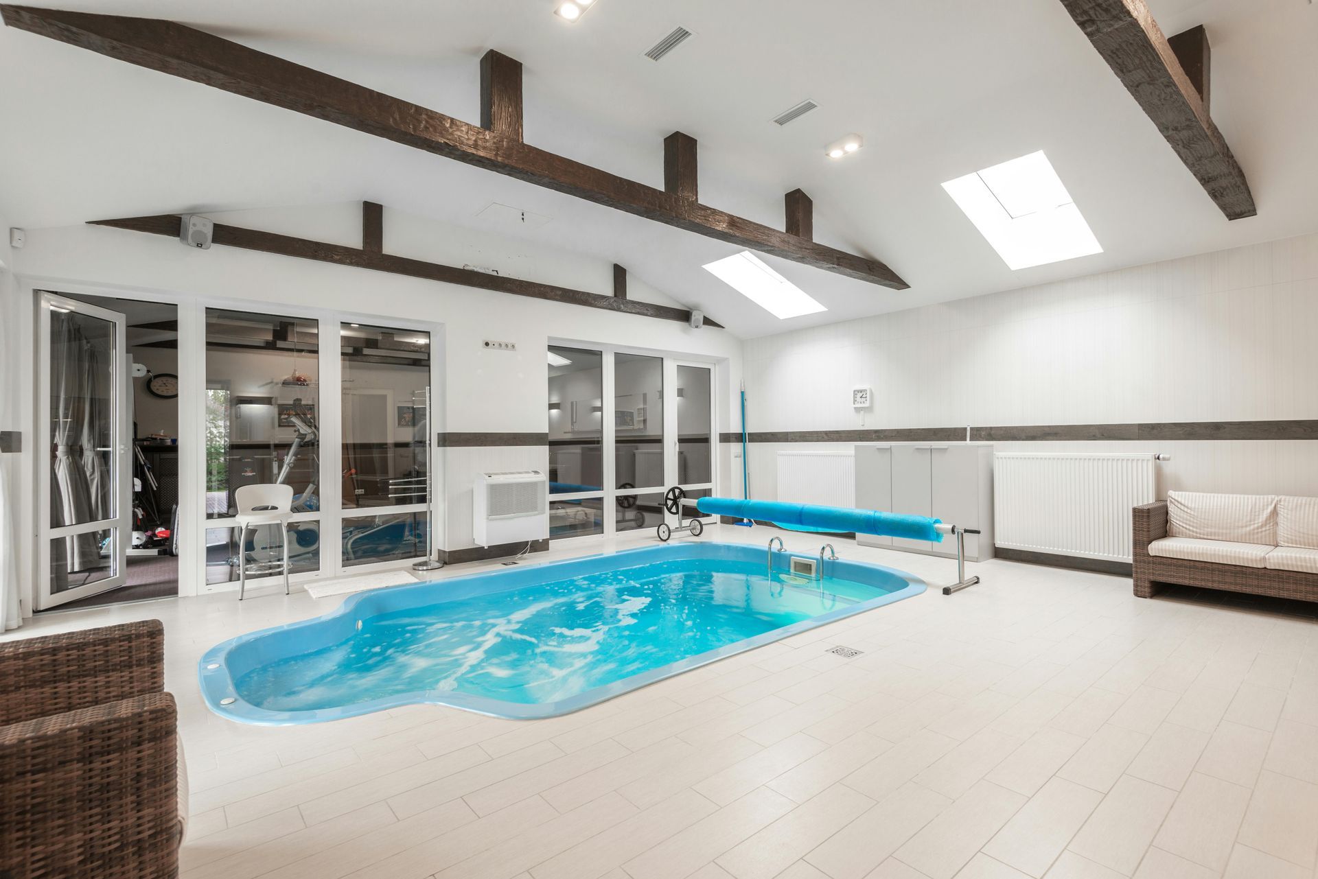 Indoor pool room with turquoise pool, white tile floor, skylights, and glass doors.