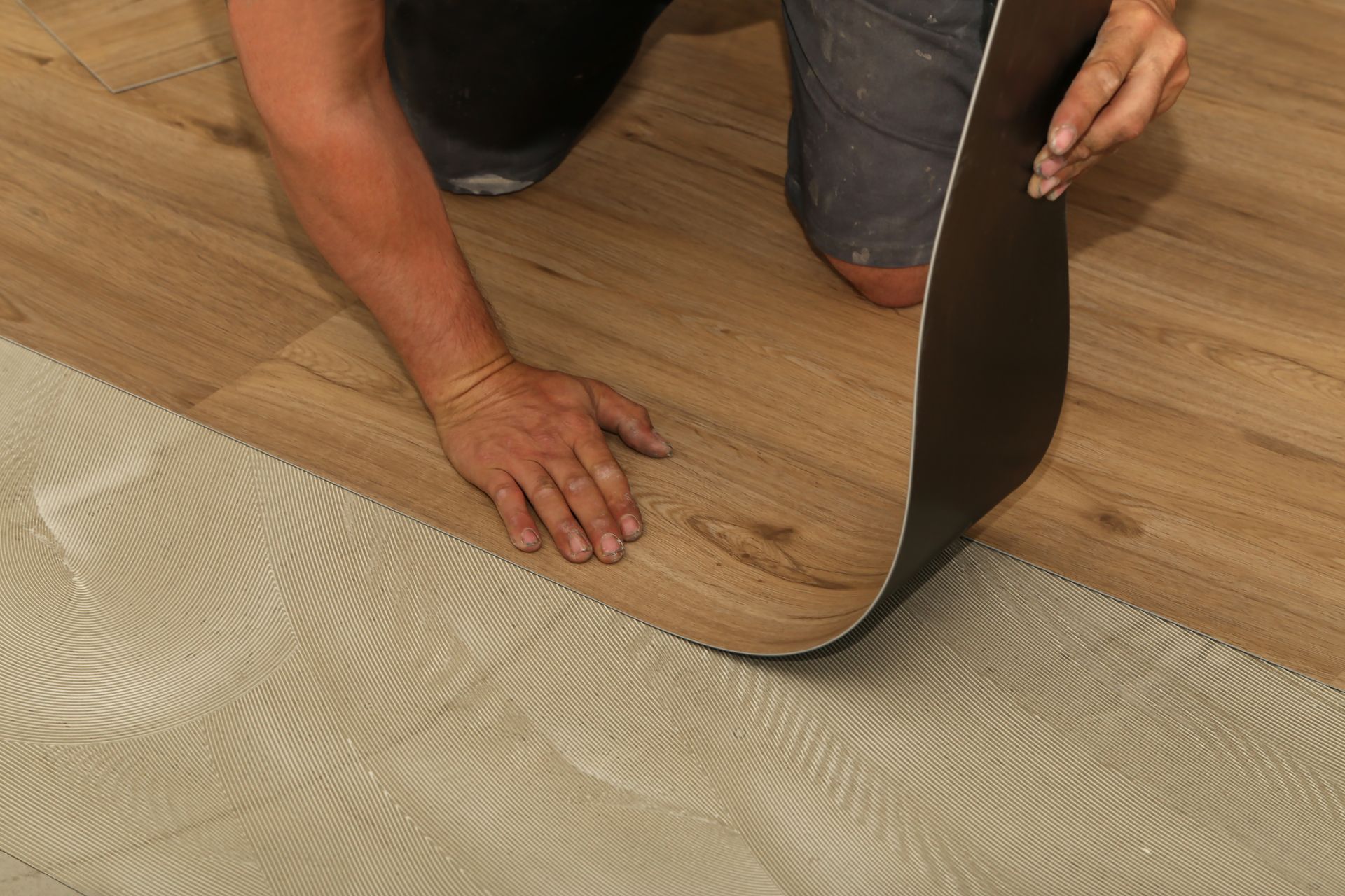 A person is laying a piece of vinyl flooring on the floor.