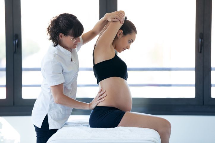 A pregnant woman is getting a massage from a nurse