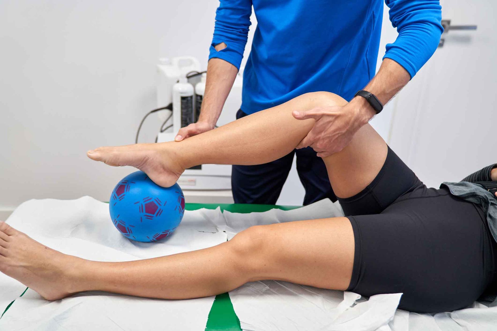 A person is laying on a bed getting their leg examined by a doctor.