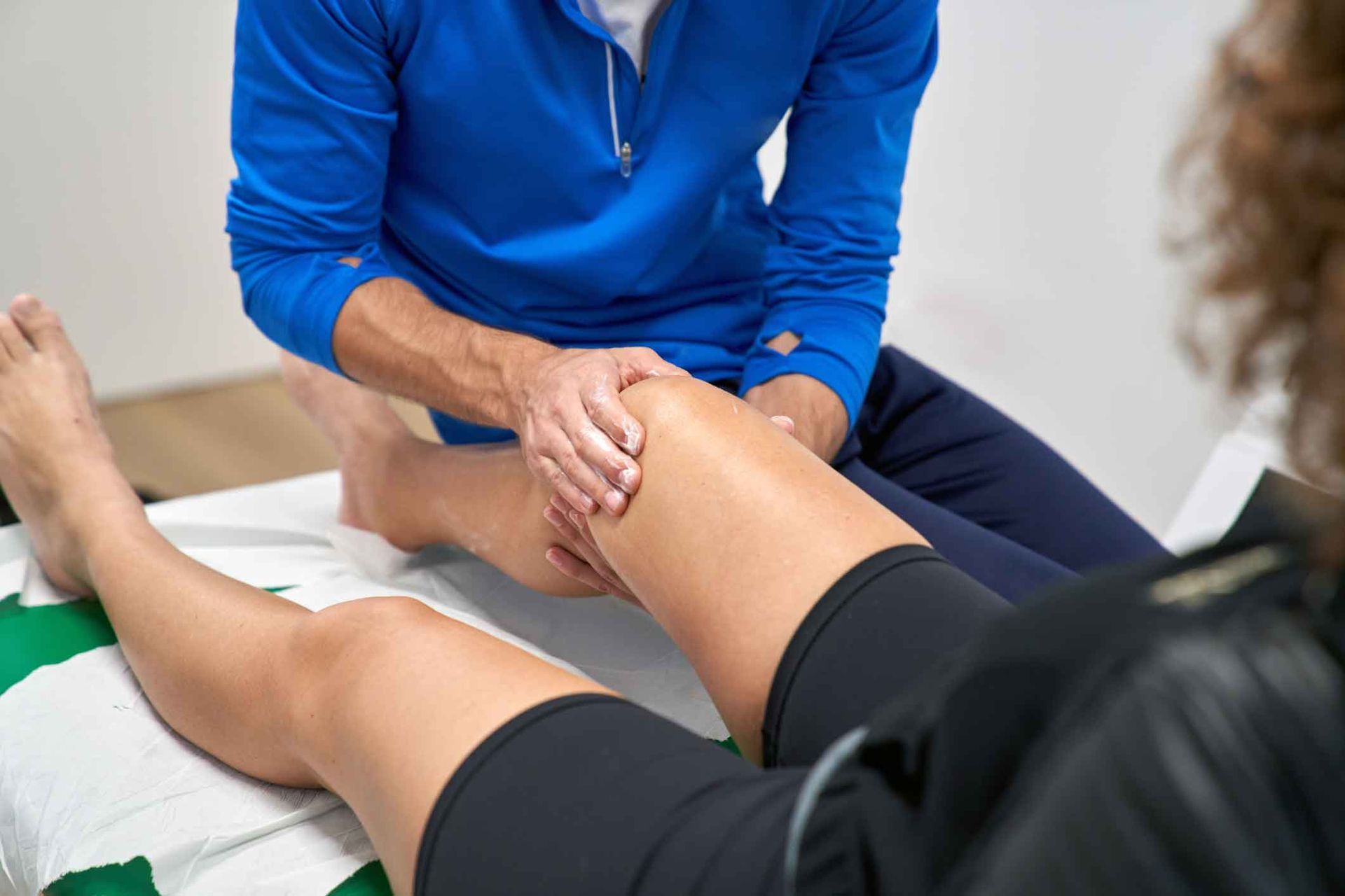 A man is giving a woman a massage on her knee.