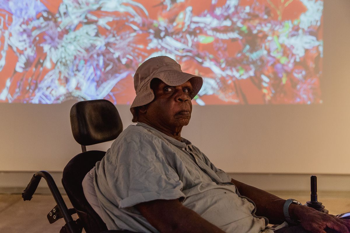 A man wearing a hat is sitting in a wheelchair
