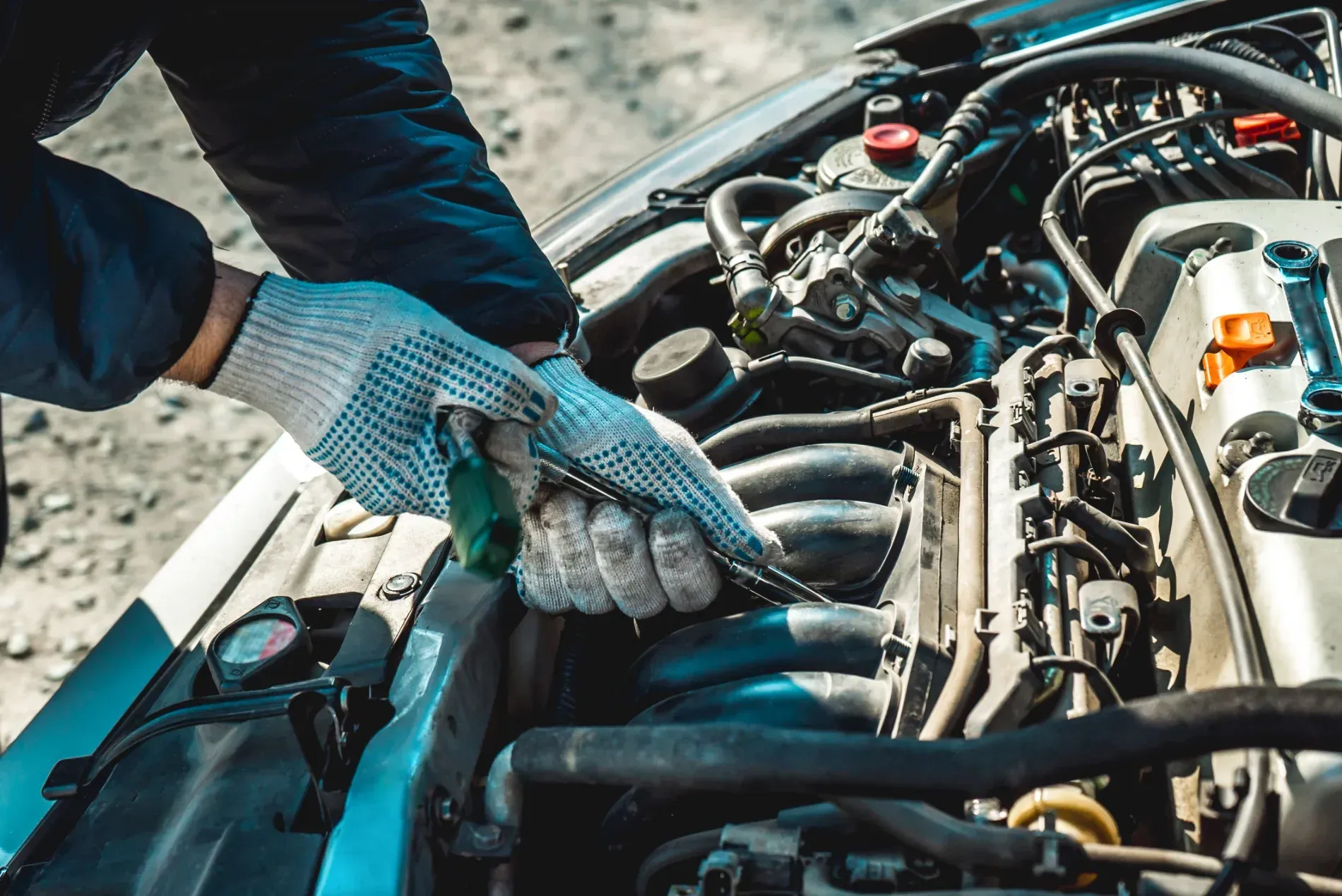 Mechanic Wearing Blue Gloves Working on An Engine with Tools in An Open Car Hood — KBX Mechanical In West Mackay, QLD