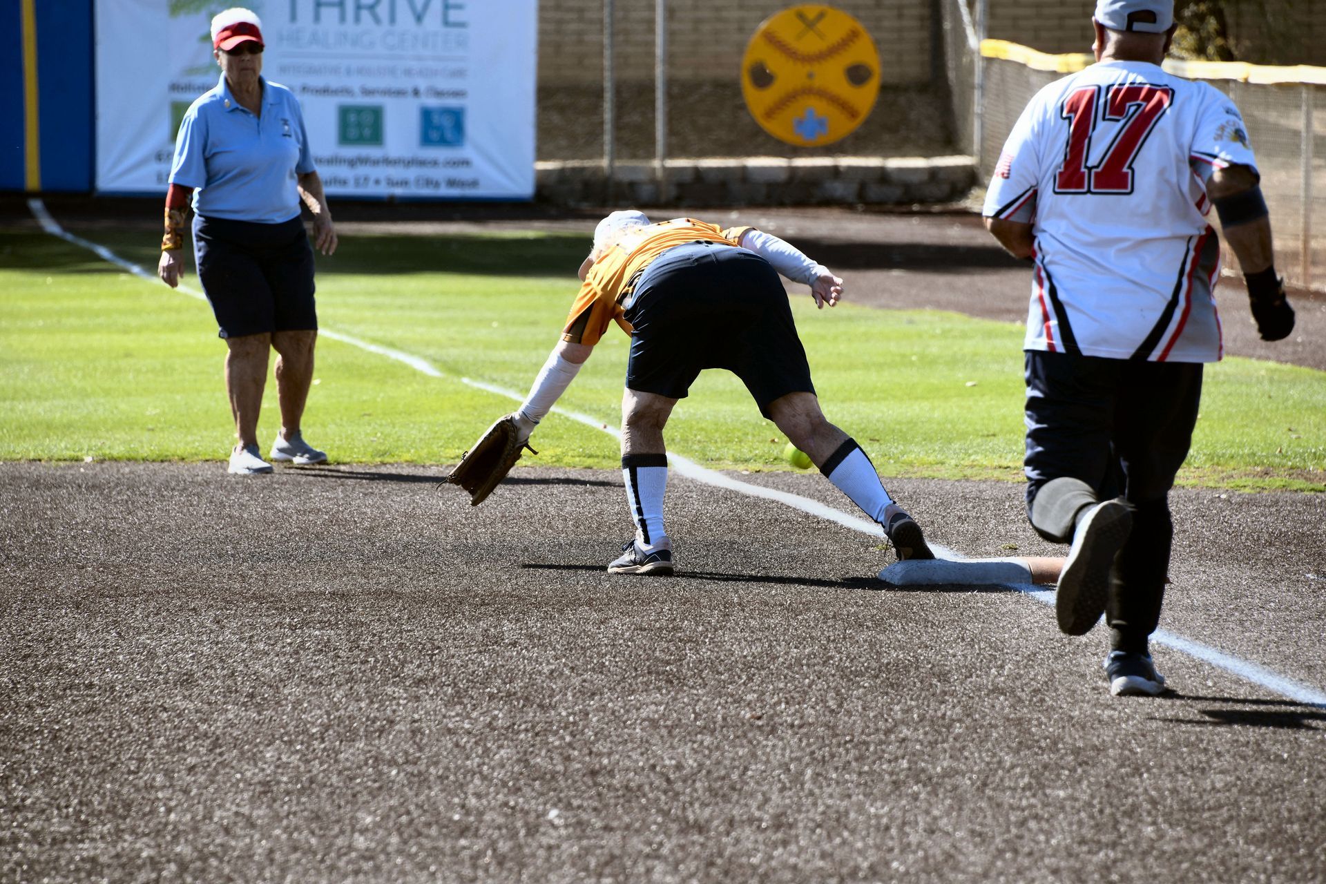 Baseball player sliding into base as another player attempts to catch the ball.