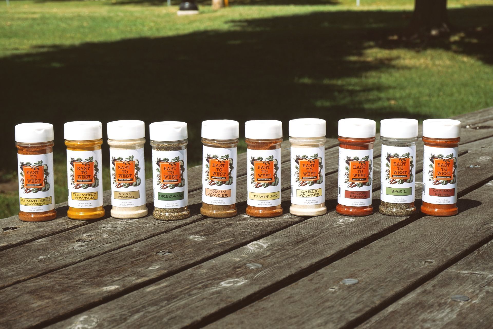 Bottles of spices are lined up on a wooden table