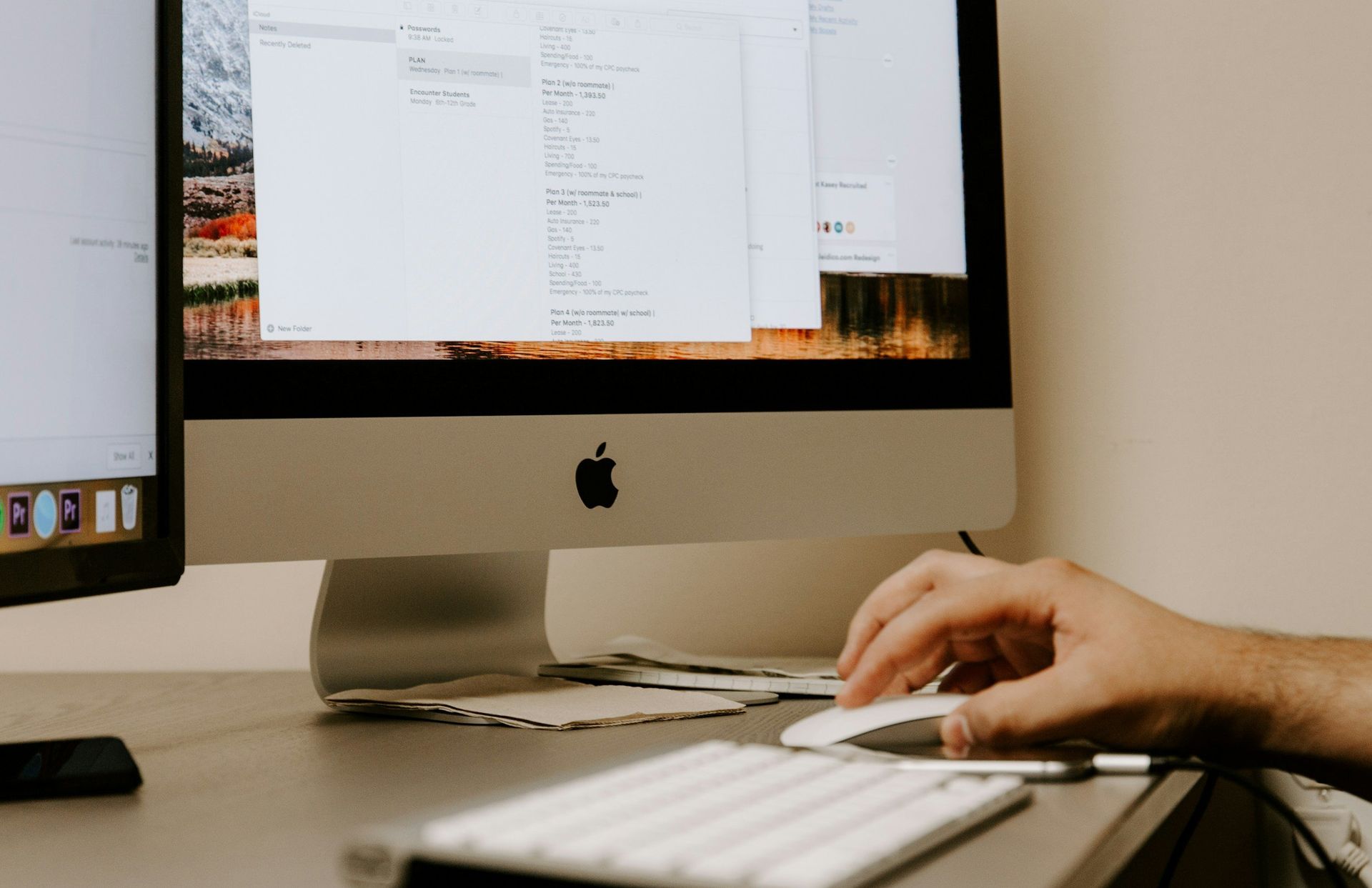 A person is typing on a keyboard in front of an apple computer.