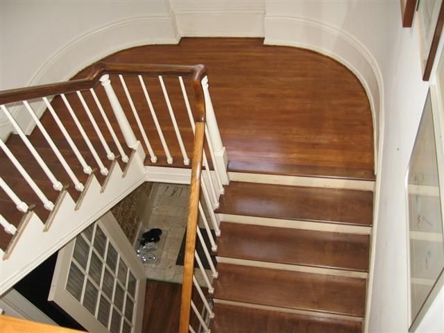 Wooden staircase with white banister in a curved hallway