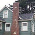 Green house with tall brick chimney and gray roof.