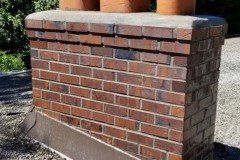 Brick chimney with clay chimney pots on a flat roof. Brown and gray tones.