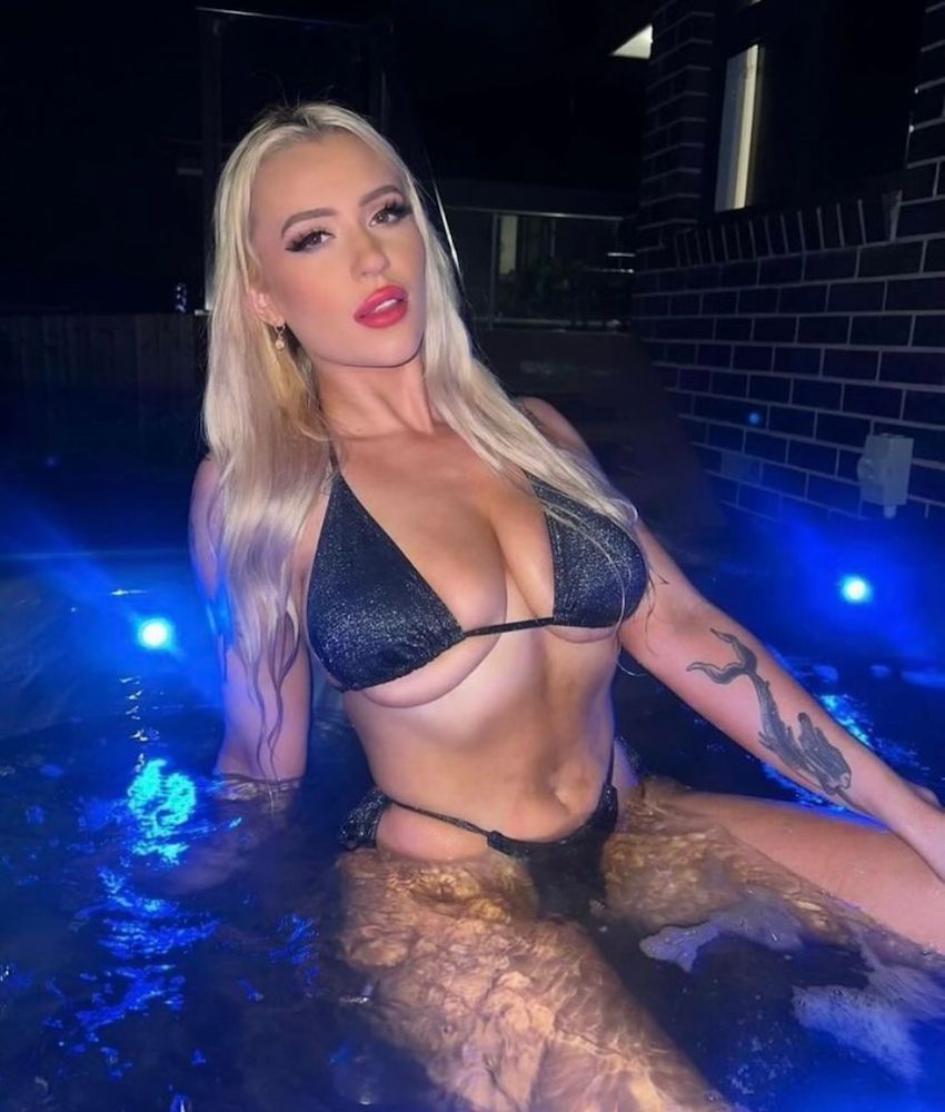 Blonde Woman in a Black Sparkly Bikini Sits in a Lit Pool at Night — Launceston Showgirls in Launceston, TAS
