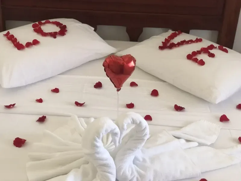 Uma cama decorada com pétalas de rosa formando a palavra