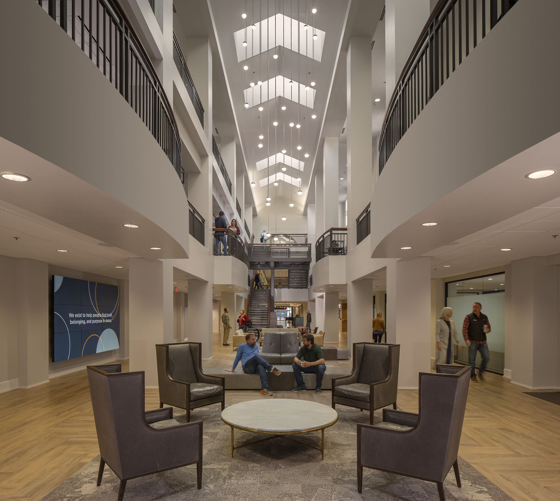 Lobby with seating, upper levels with walkways, high ceiling with skylights, people.