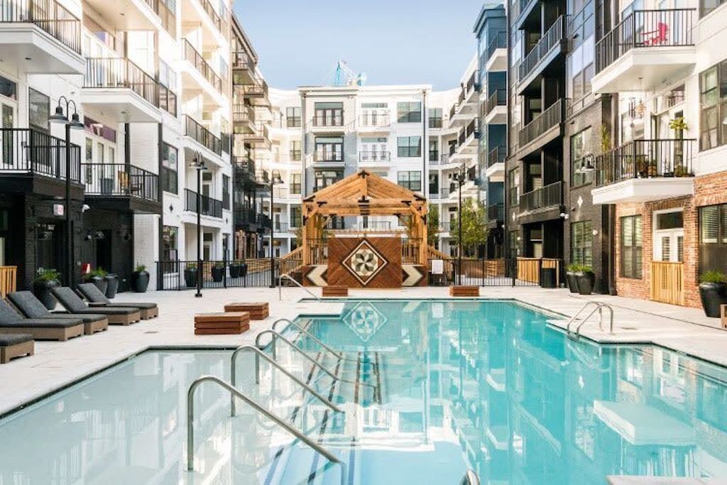 Pool and lounge area in a modern apartment complex. Pool with lounge chairs and gazebo in the background.