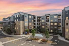 Modern multi-story apartment building with a sunset sky.