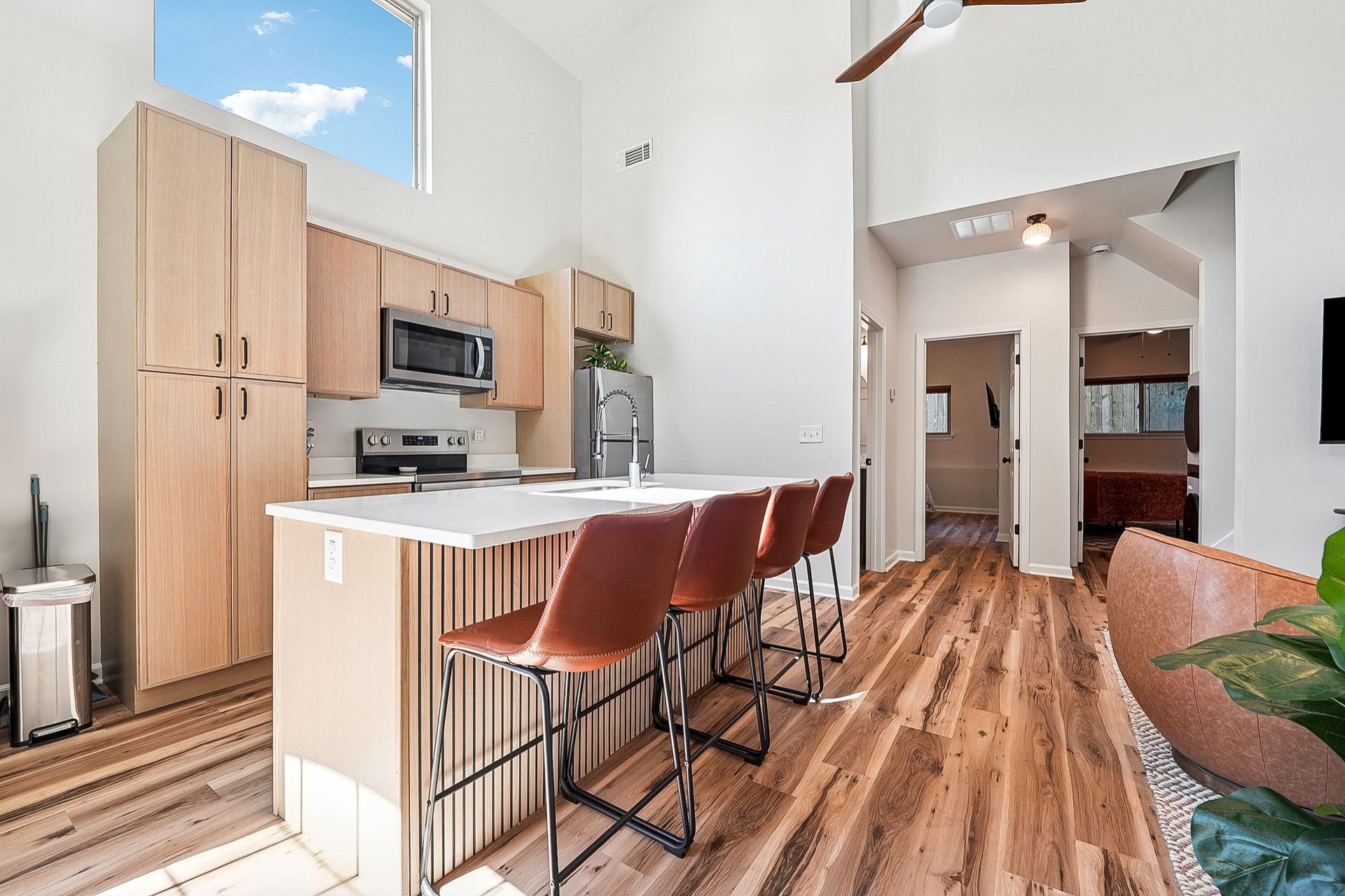 Modern kitchen with wood cabinets, island with stools, and hardwood floors.
