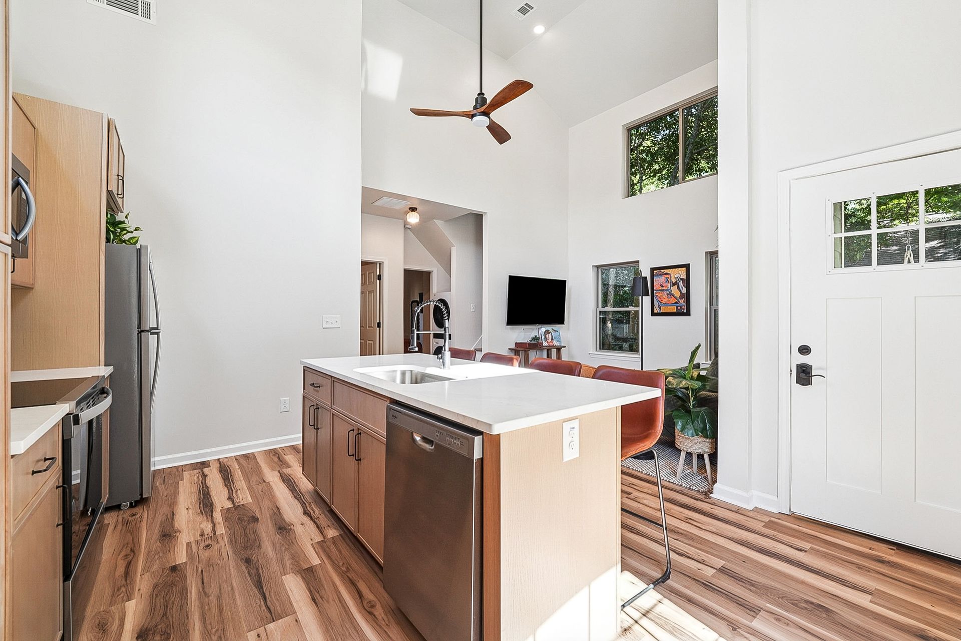 Kitchen with island, stainless steel appliances, high ceilings, and wooden floors.
