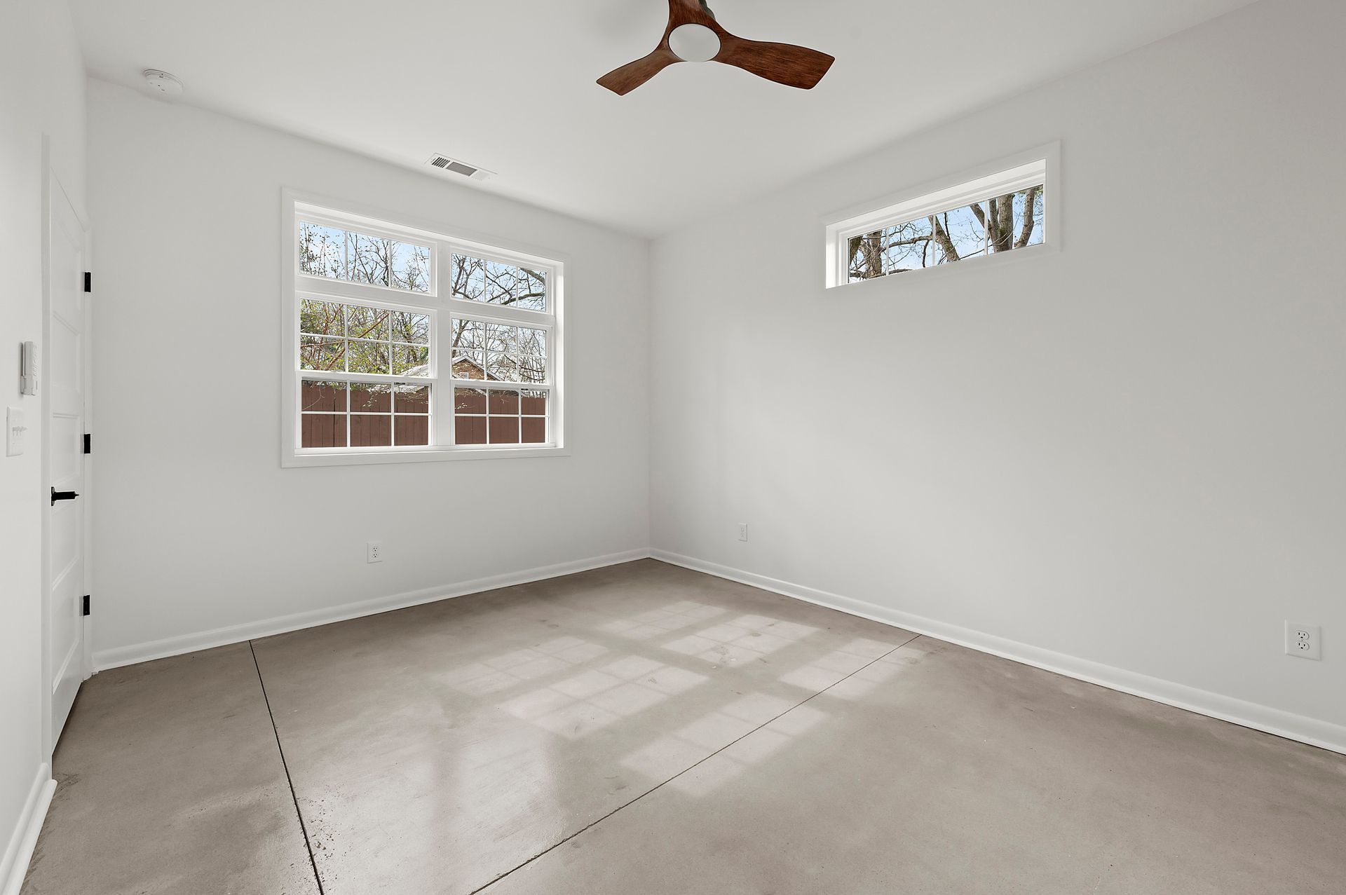 Empty room with two windows, a ceiling fan, and carpeted floor. White walls.