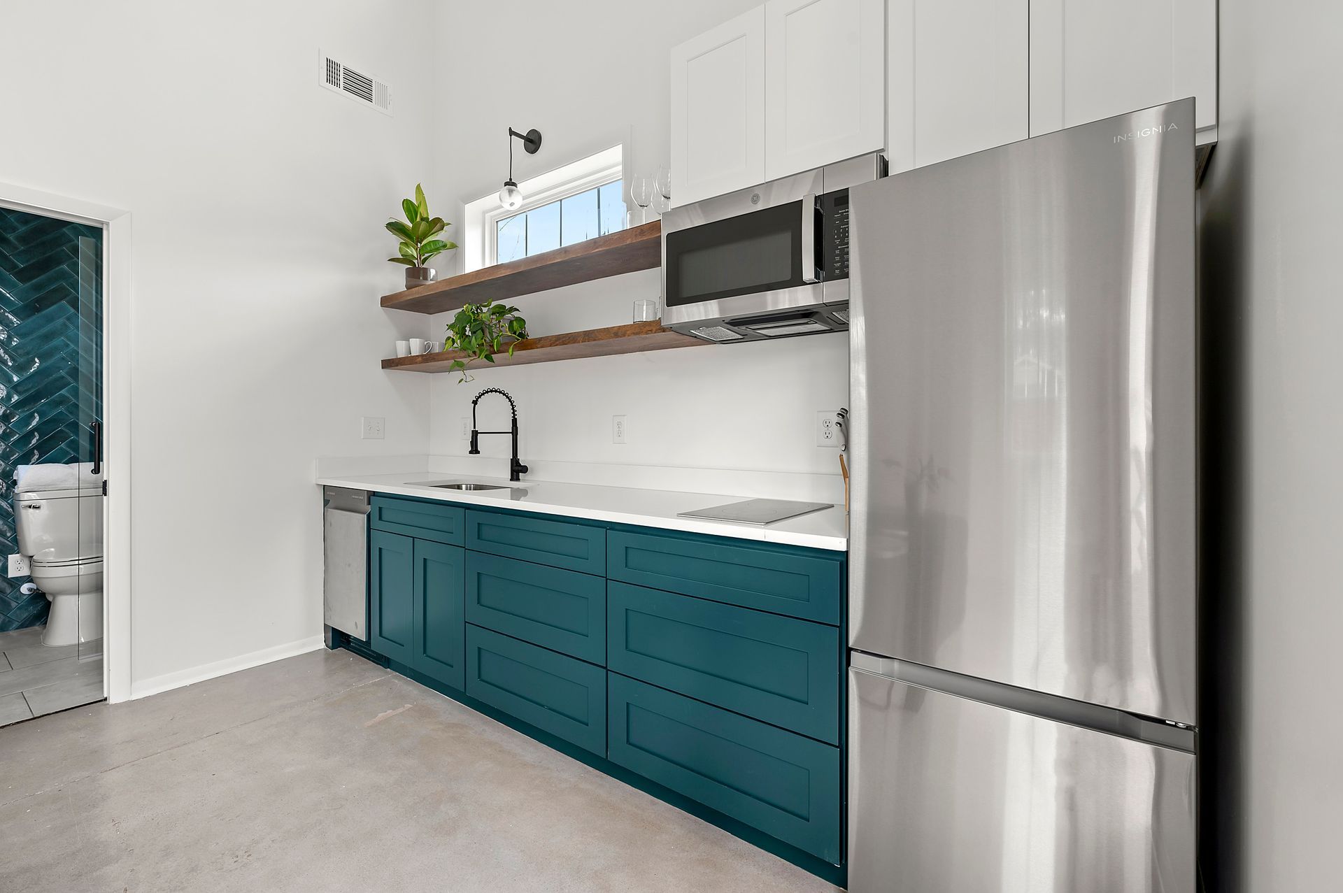 Modern kitchen with teal cabinets, stainless steel appliances, and open shelving.