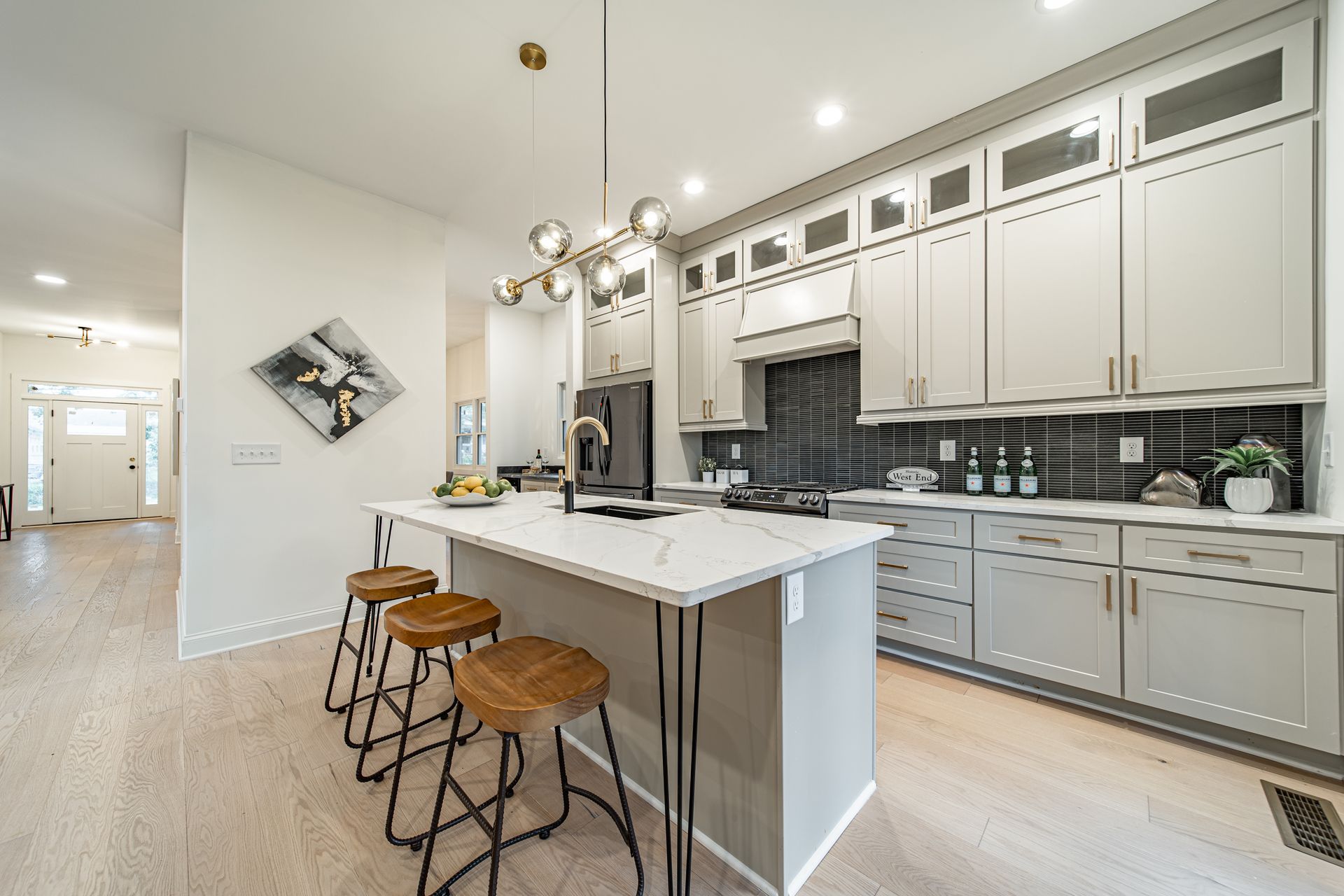 Modern kitchen with gray cabinets, white countertops, and a central island with stools.