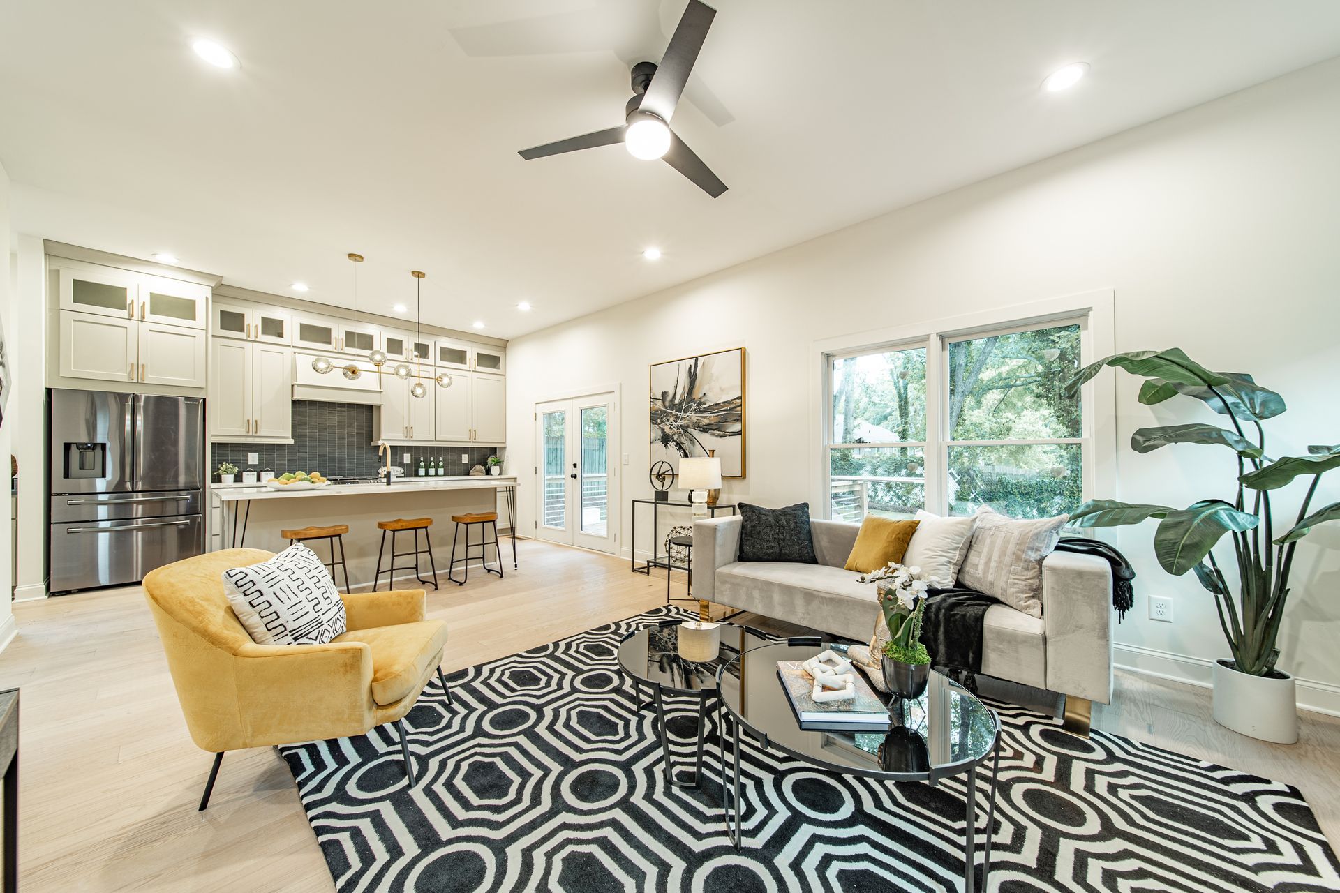 Open-concept living space with a kitchen, living area, and glass doors. Features light wood flooring, gray walls, and modern furniture.