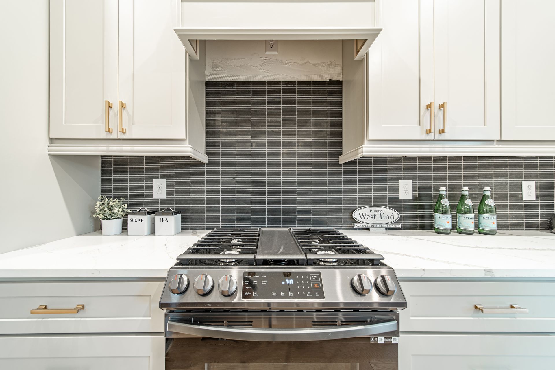 Kitchen with stainless steel stove, white cabinets, and gray backsplash.