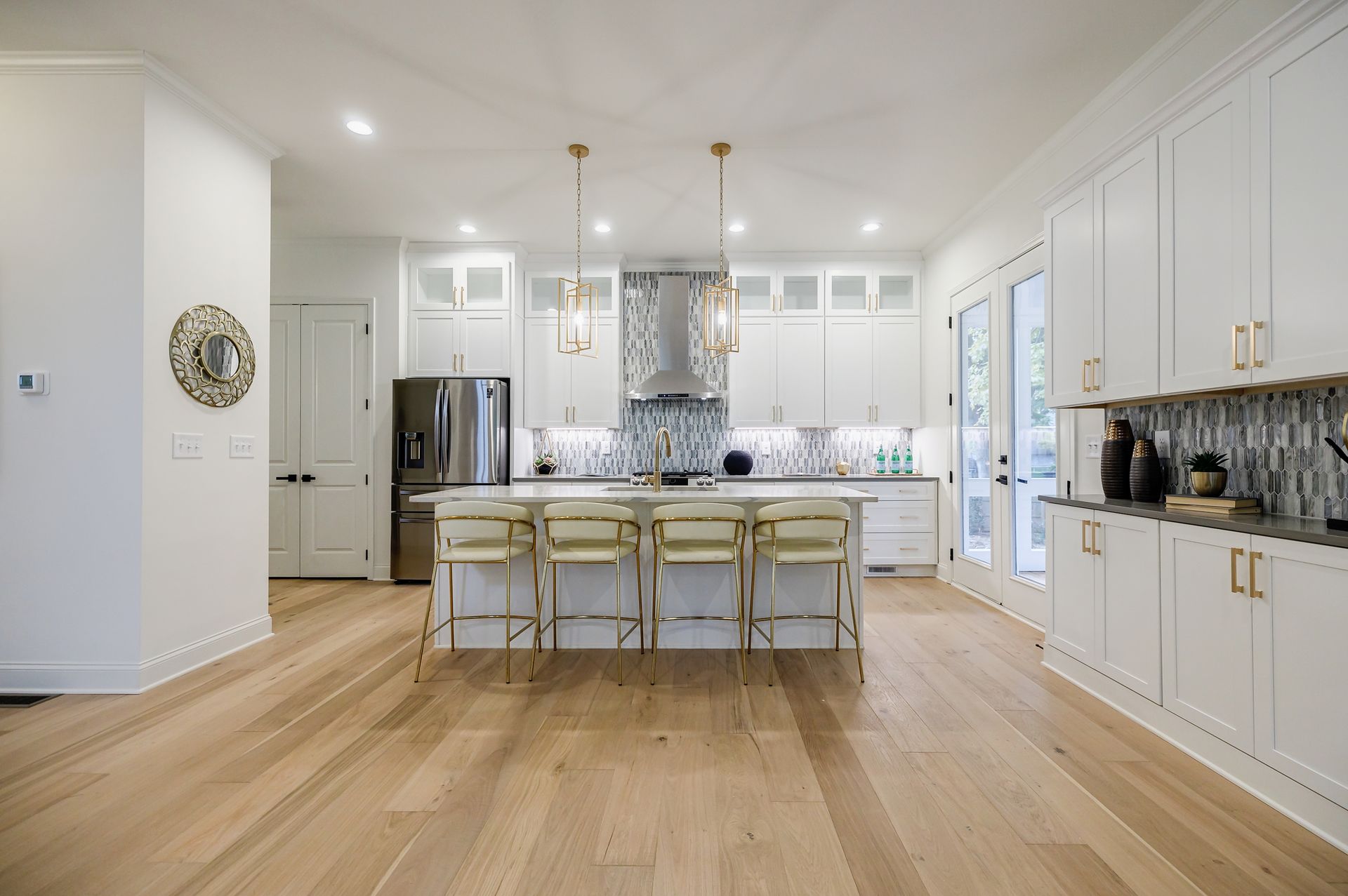 Bright white kitchen with a large island, stainless steel appliances, and gold accents.