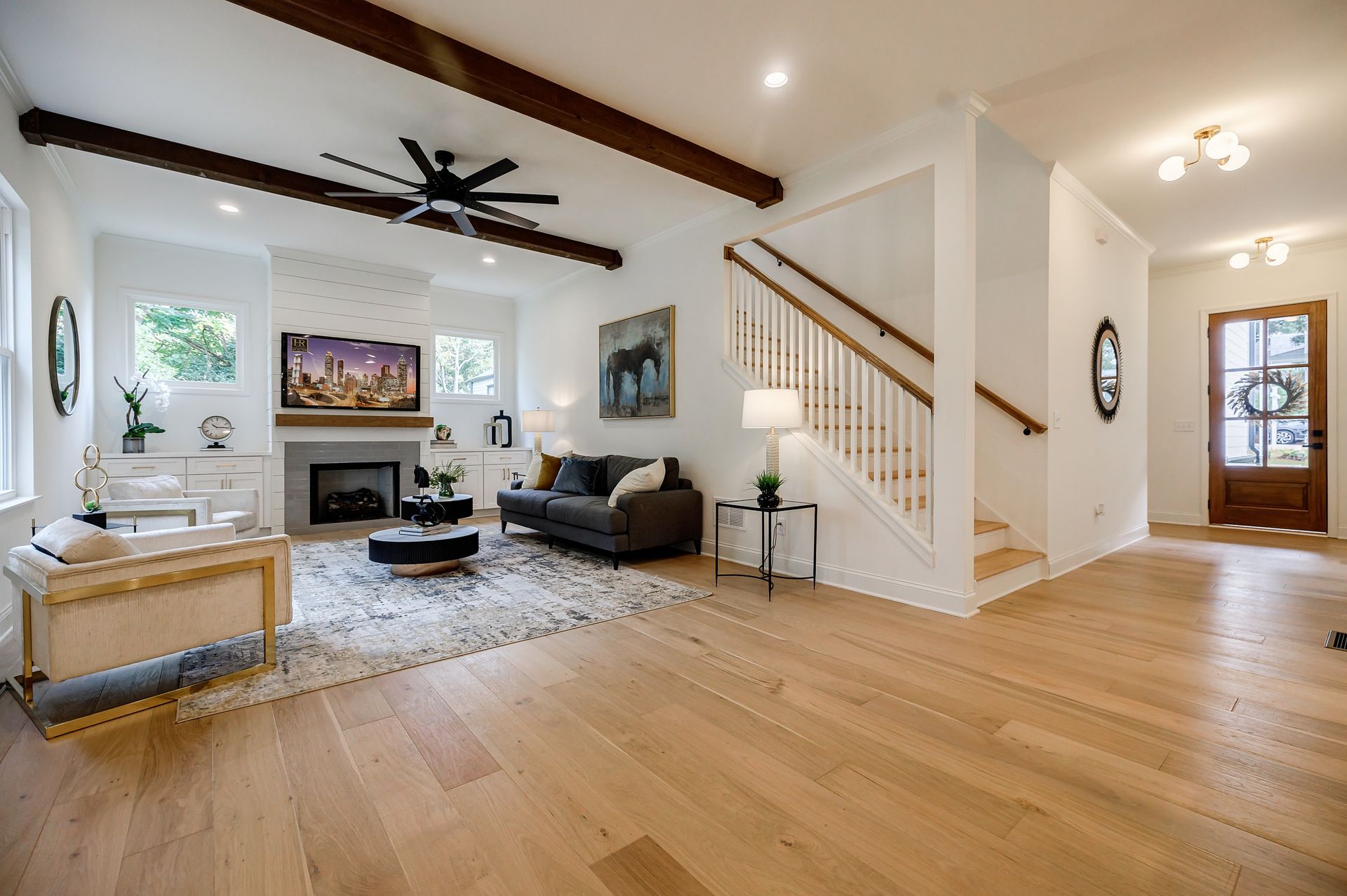 Living room with wood floors, fireplace, and staircase. Furnished with a couch, rug, and coffee table.