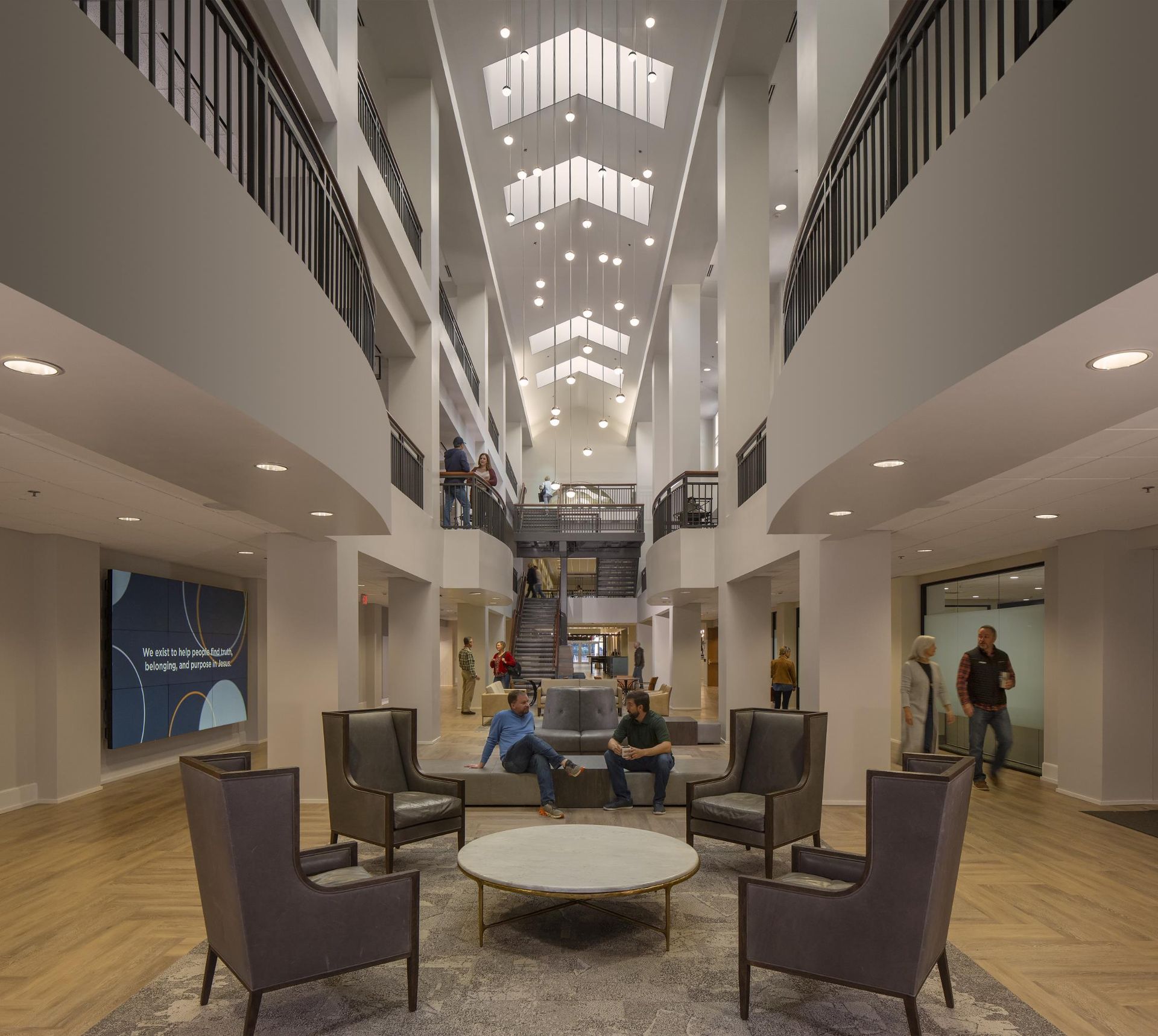 Spacious modern lobby with seating area; multiple levels with balconies; skylights overhead. People visible.