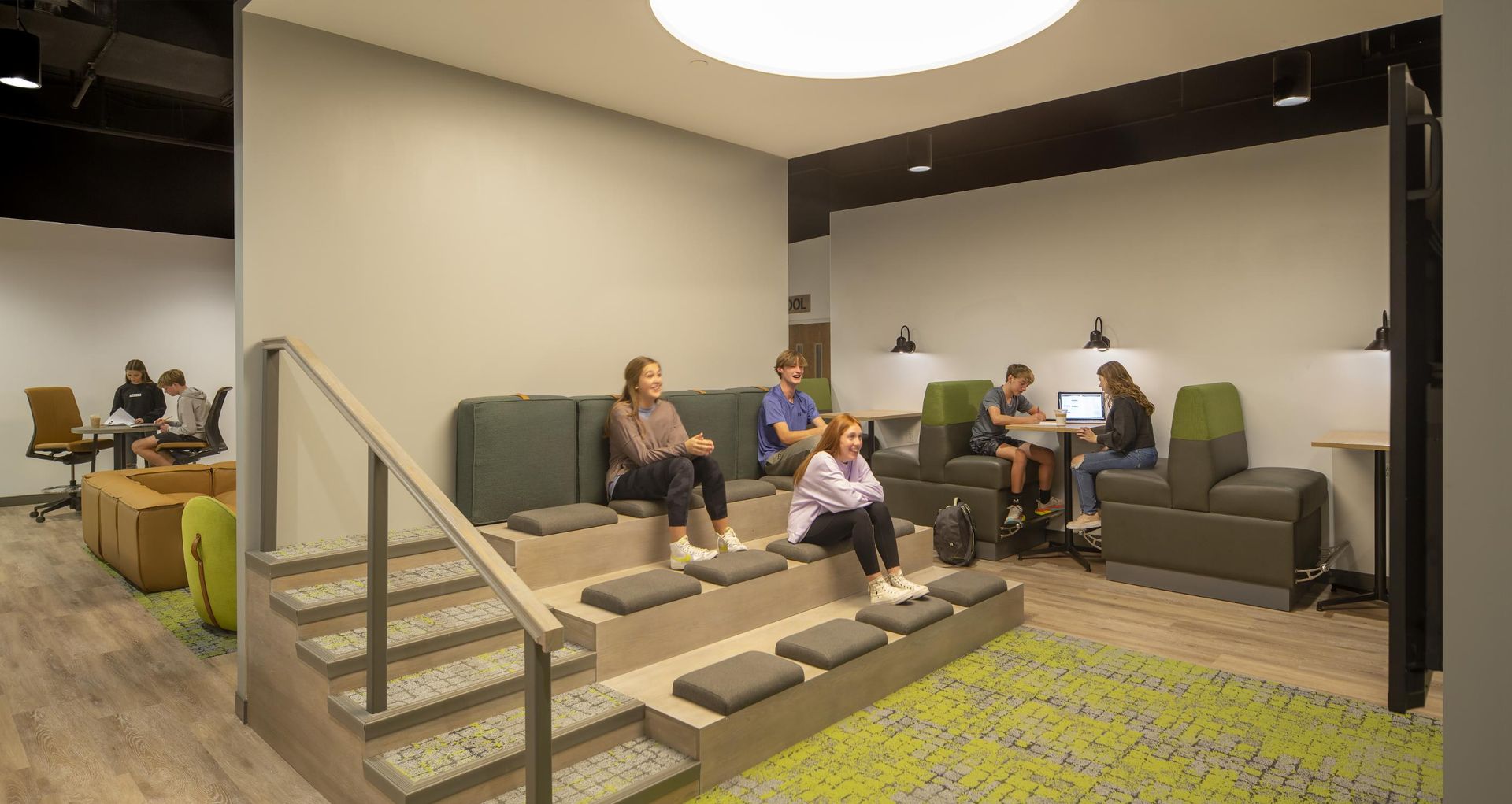 Students in a modern study lounge with tiered seating and individual study booths.