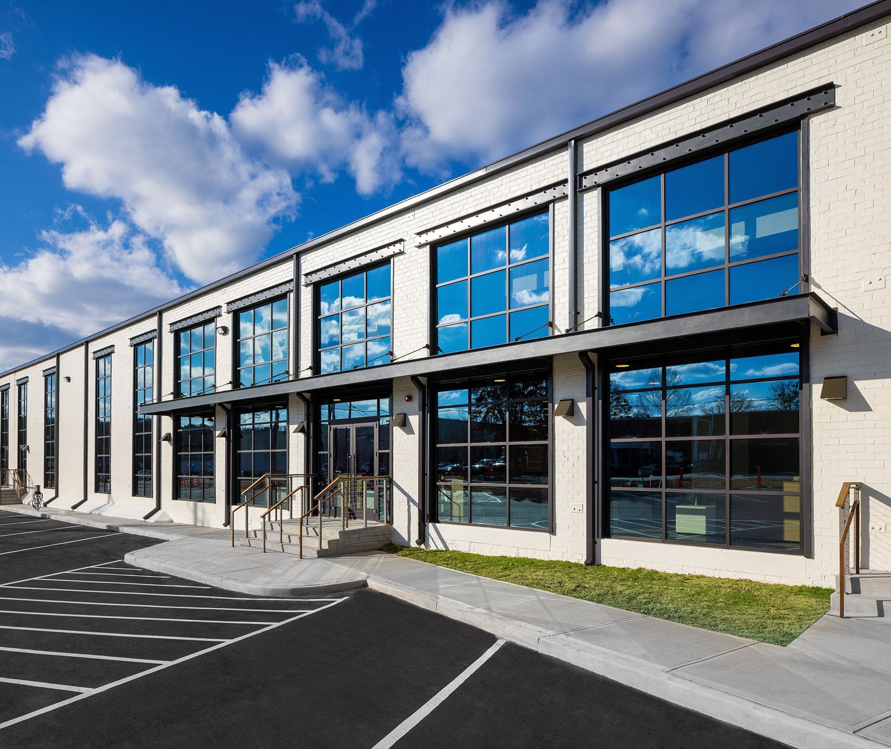 Modern brick building with large windows and awnings. Cloudy blue sky.