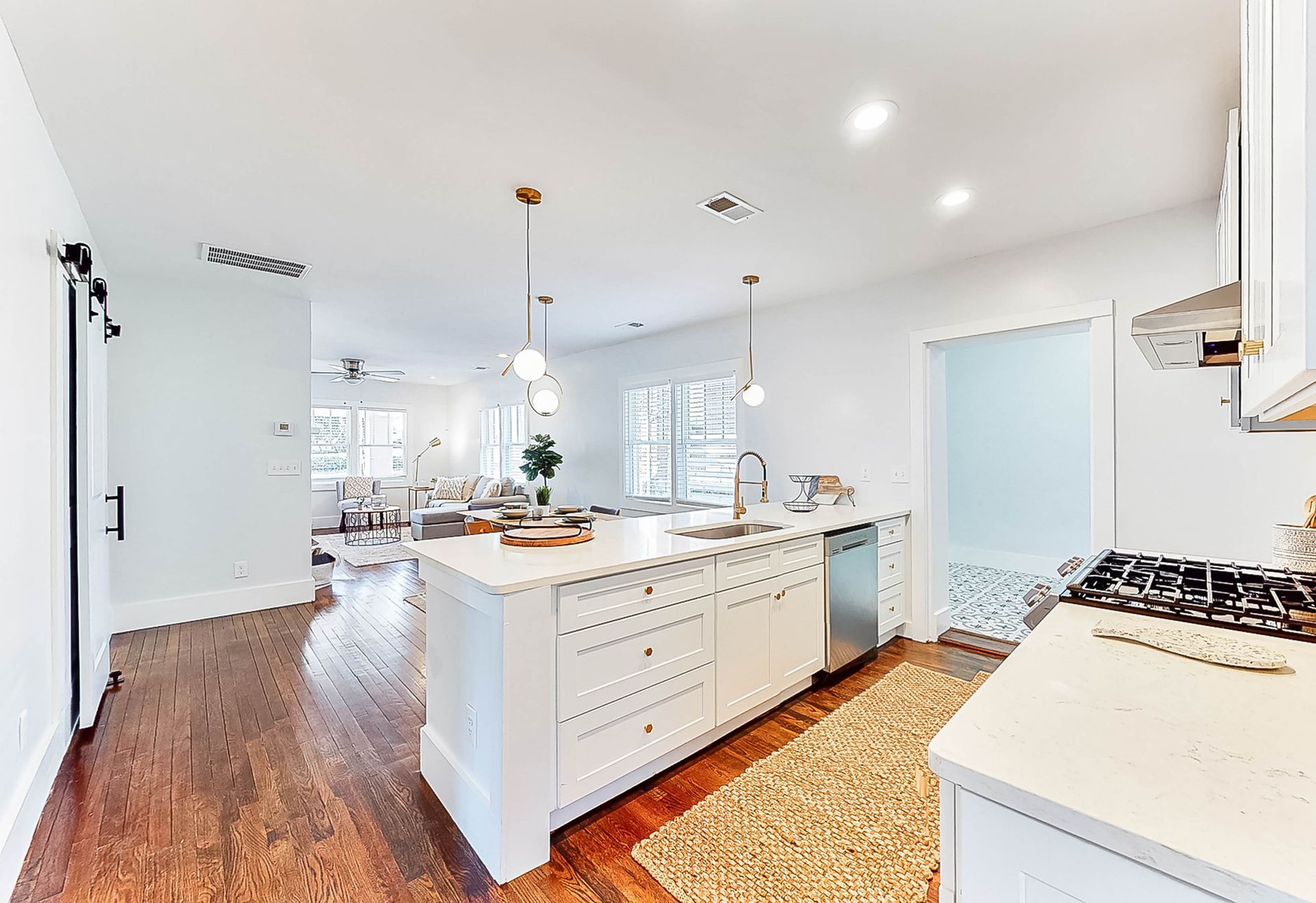 White kitchen with island, sink, and open view to living area with wood floors.