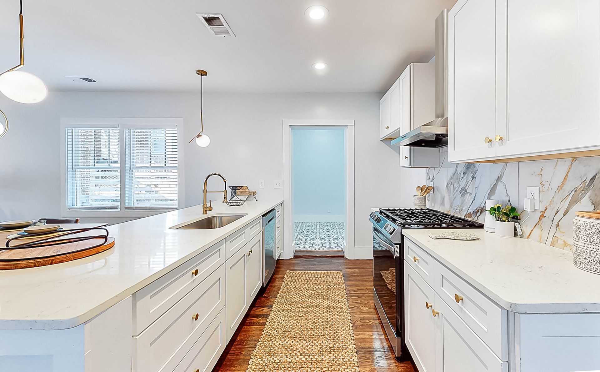 Bright white kitchen with a large island, stainless steel appliances, and gold accents.