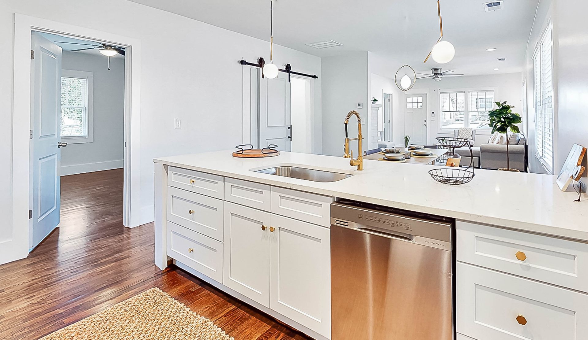 White kitchen with island, stainless steel appliances, and open layout.